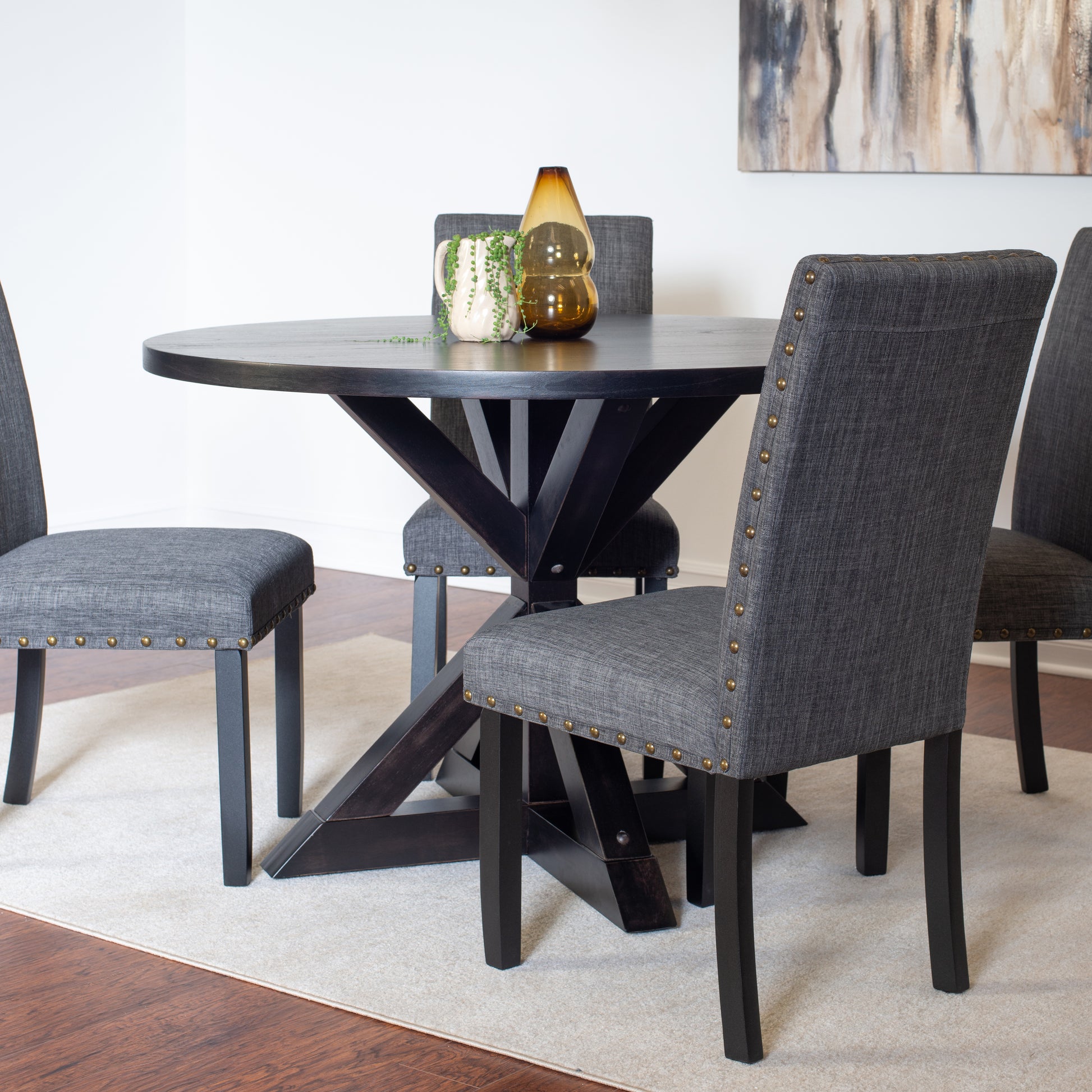 Dark wood round dining table with grey upholstered chairs