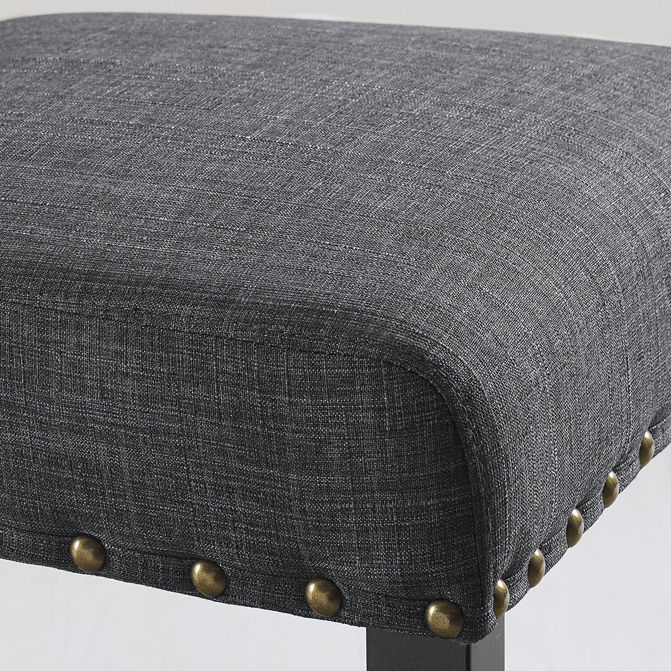 Dark gray upholstered stool seat with brass nailhead trim