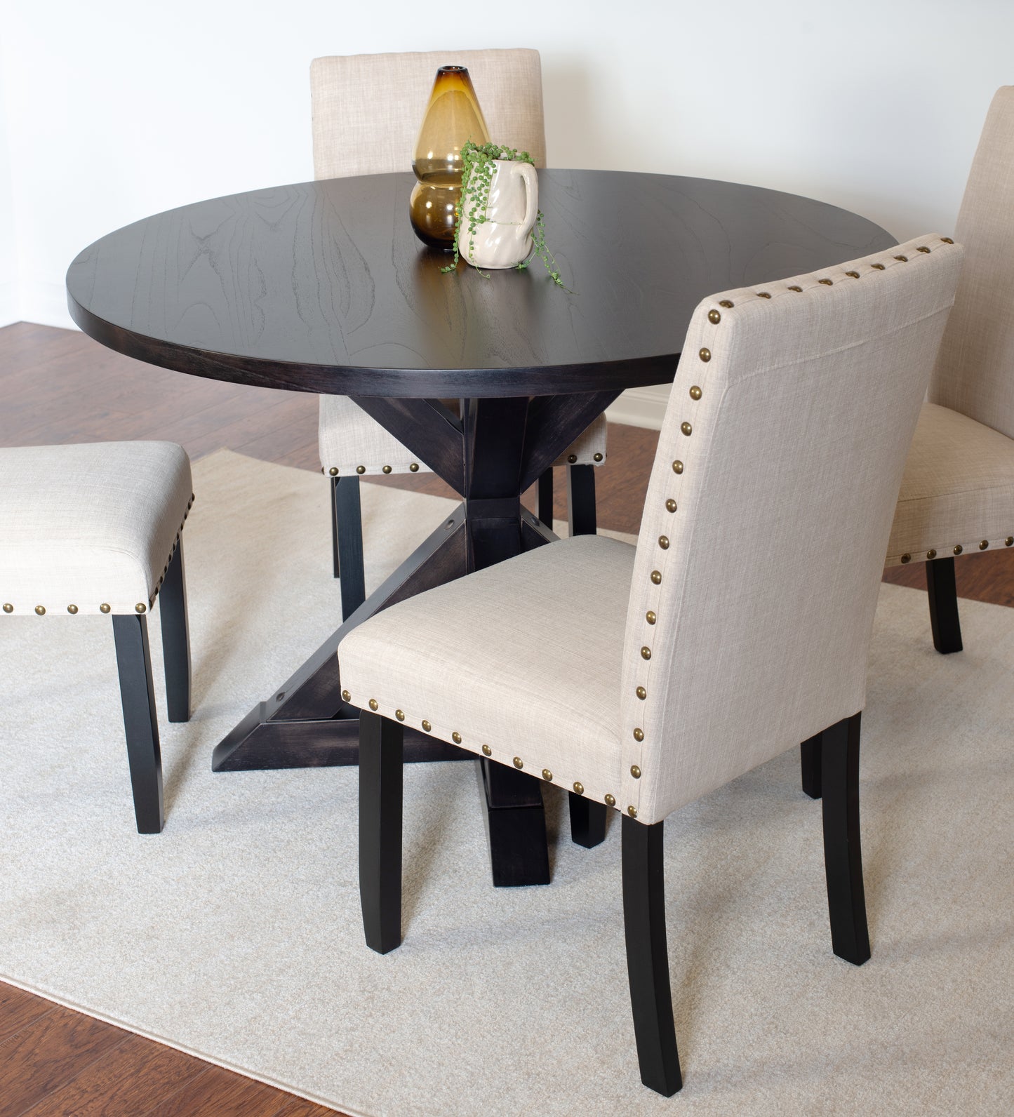 Dark oak round dining table with upholstered neutral chairs