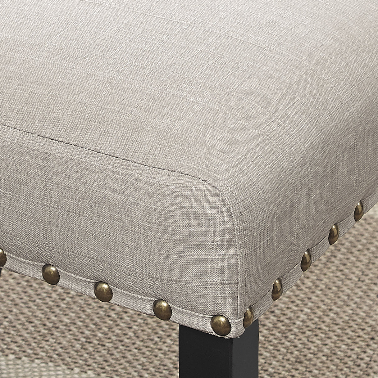 Beige linen upholstered ottoman with brass nailhead trim details