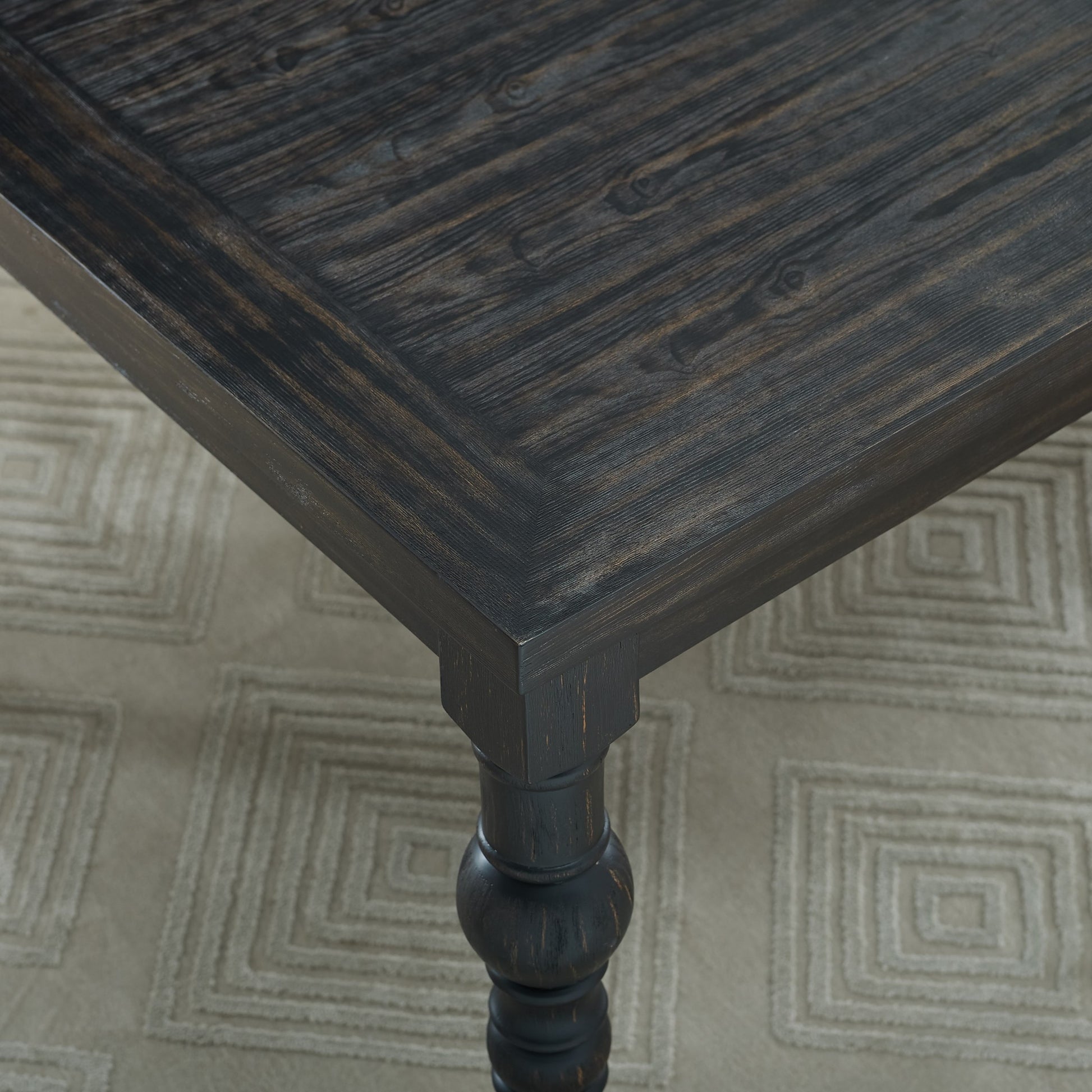 Dark wood dining table top detail with rustic finish and carved leg