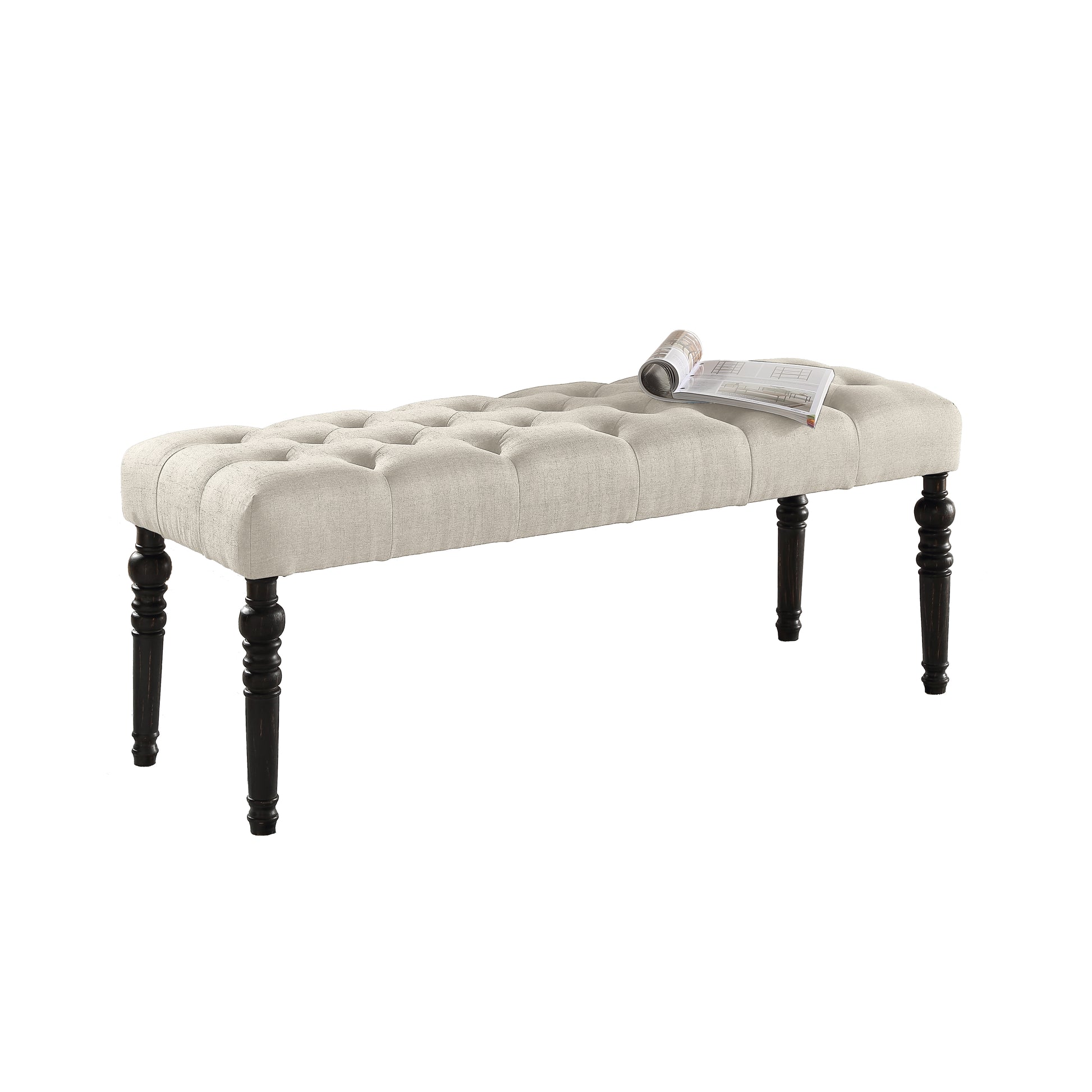 Tufted beige linen ottoman with dark turned legs and magazine