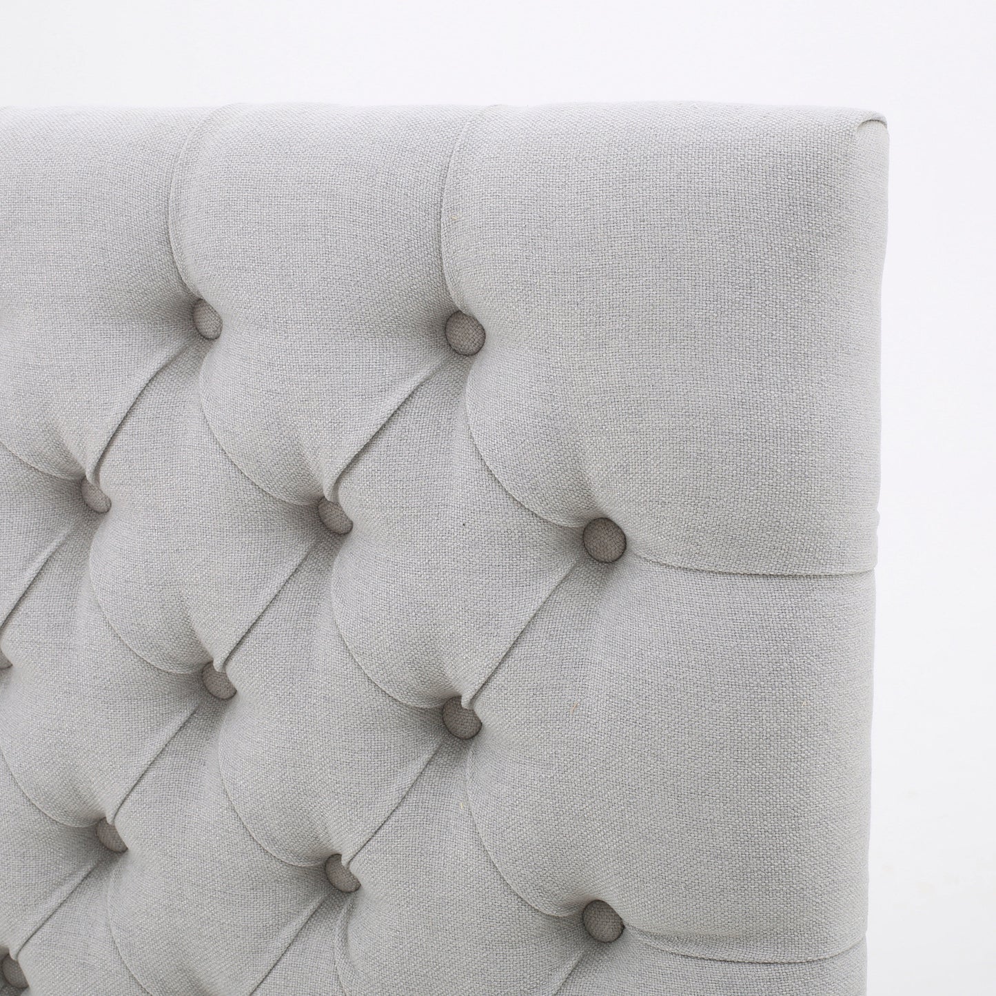 Light grey fabric headboard with diamond button tufting for a modern bedroom