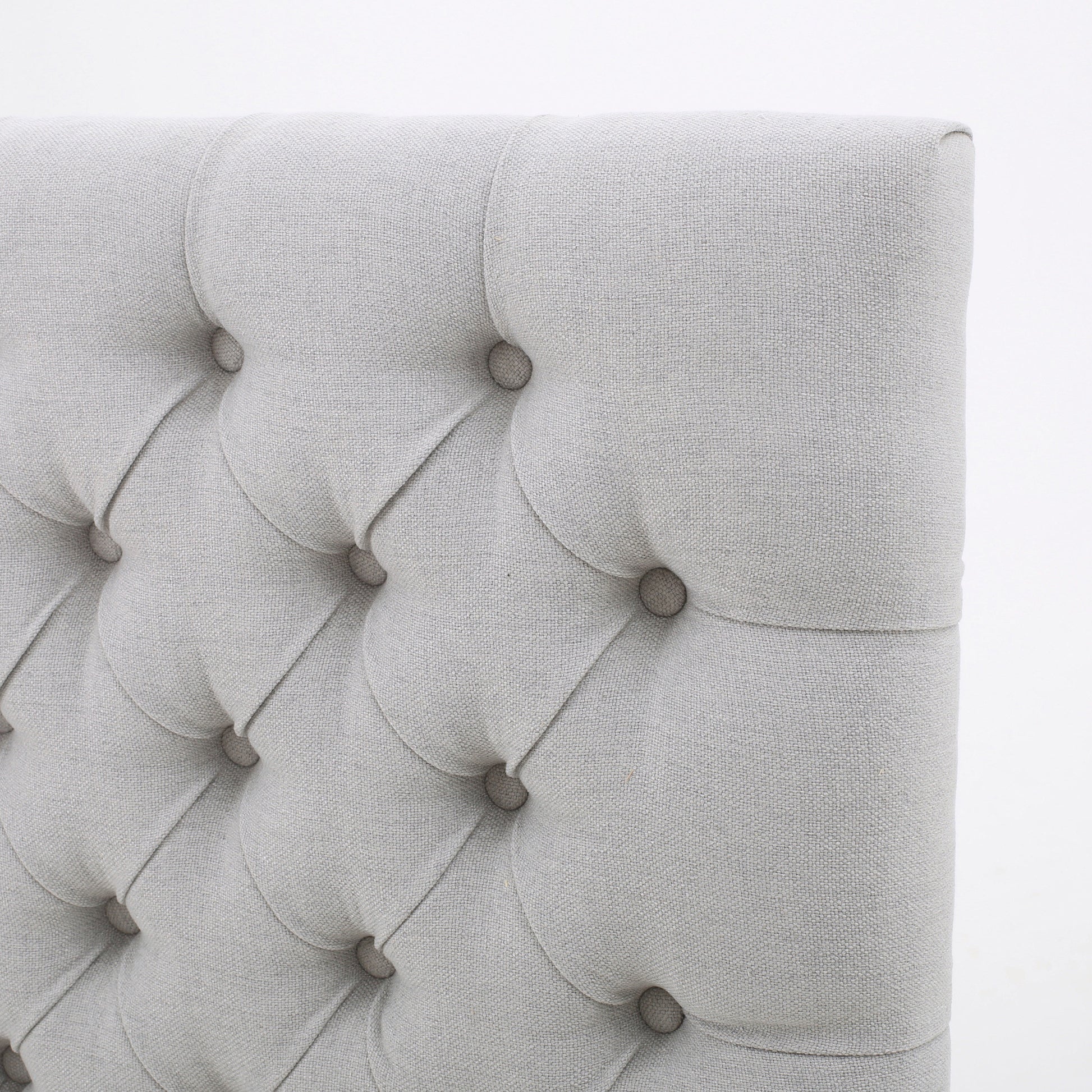 Light grey fabric headboard with diamond button tufting for a modern bedroom
