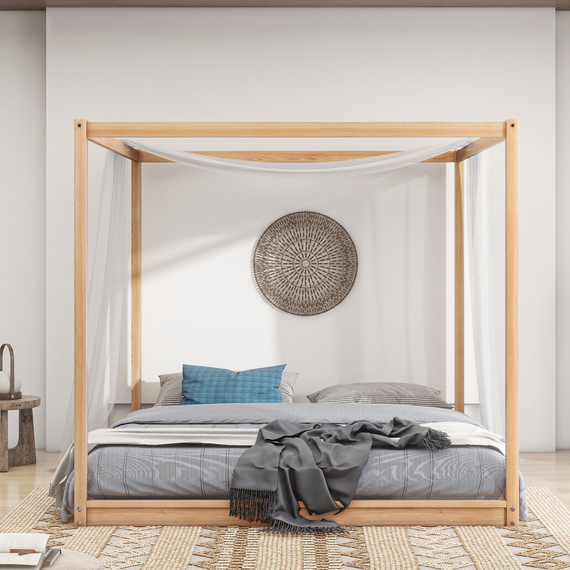 Natural wood fourposter bed with sheer drapes and striped bedding