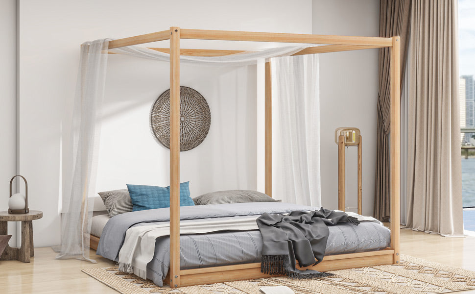 Natural wood fourposter bed with sheer drapes and striped bedding