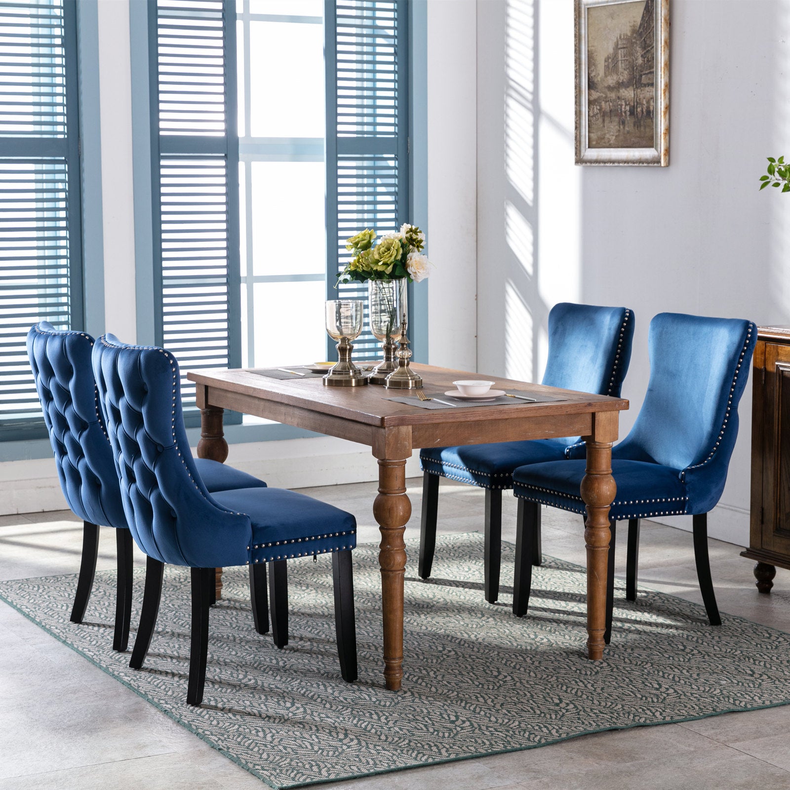 Deep blue velvet dining chairs with tufted backs and silver nailhead trim