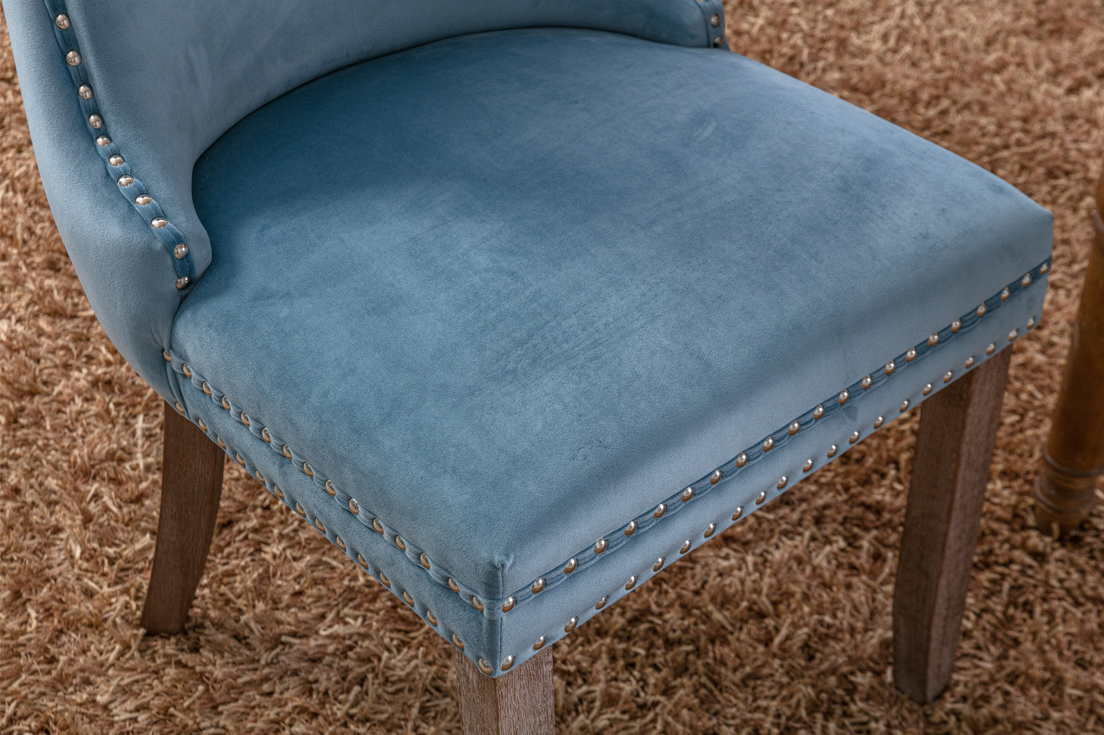 Blue velvet dining chair with brass nailhead trim and dark wood legs