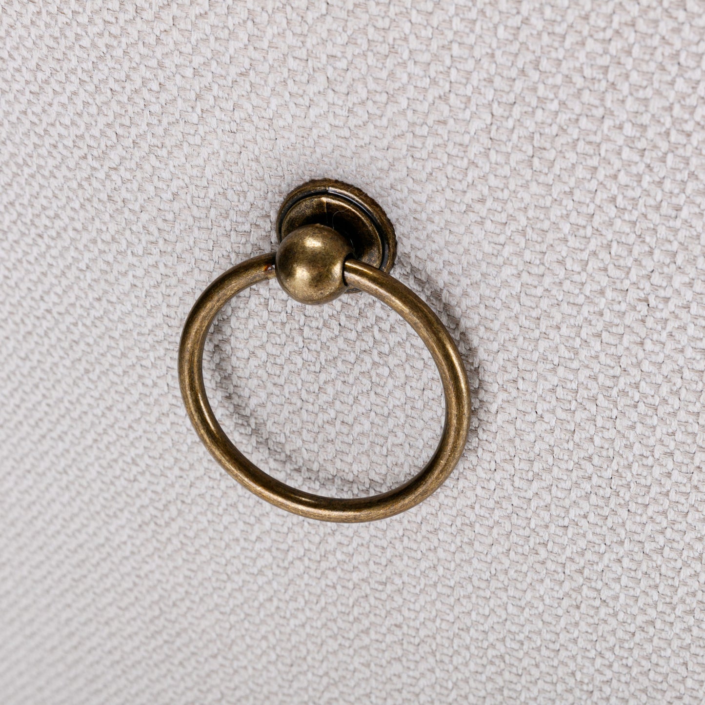 Antique brass ring pull on textured beige fabric drawer