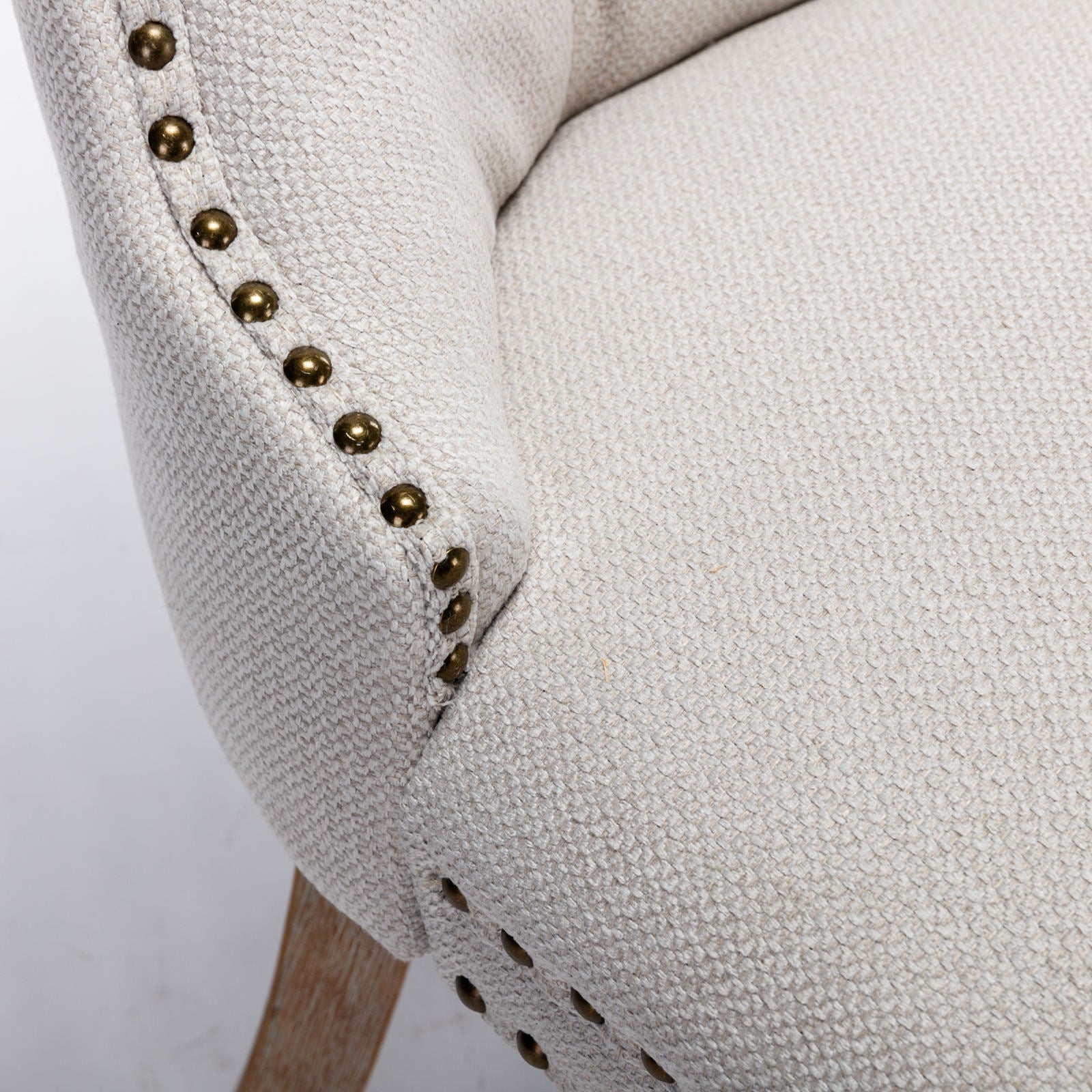 Cream textured fabric accent chair with brass nailhead trim