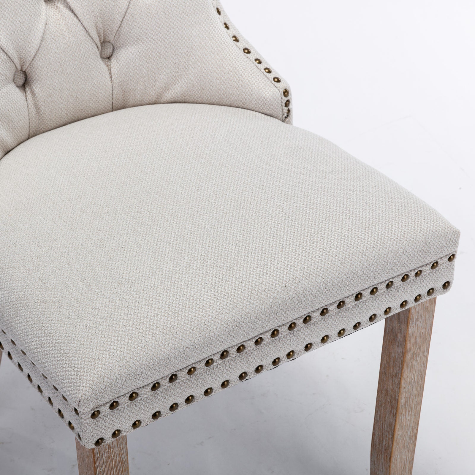 Tufted beige fabric dining chair with antique brass nailhead trim and wooden legs
