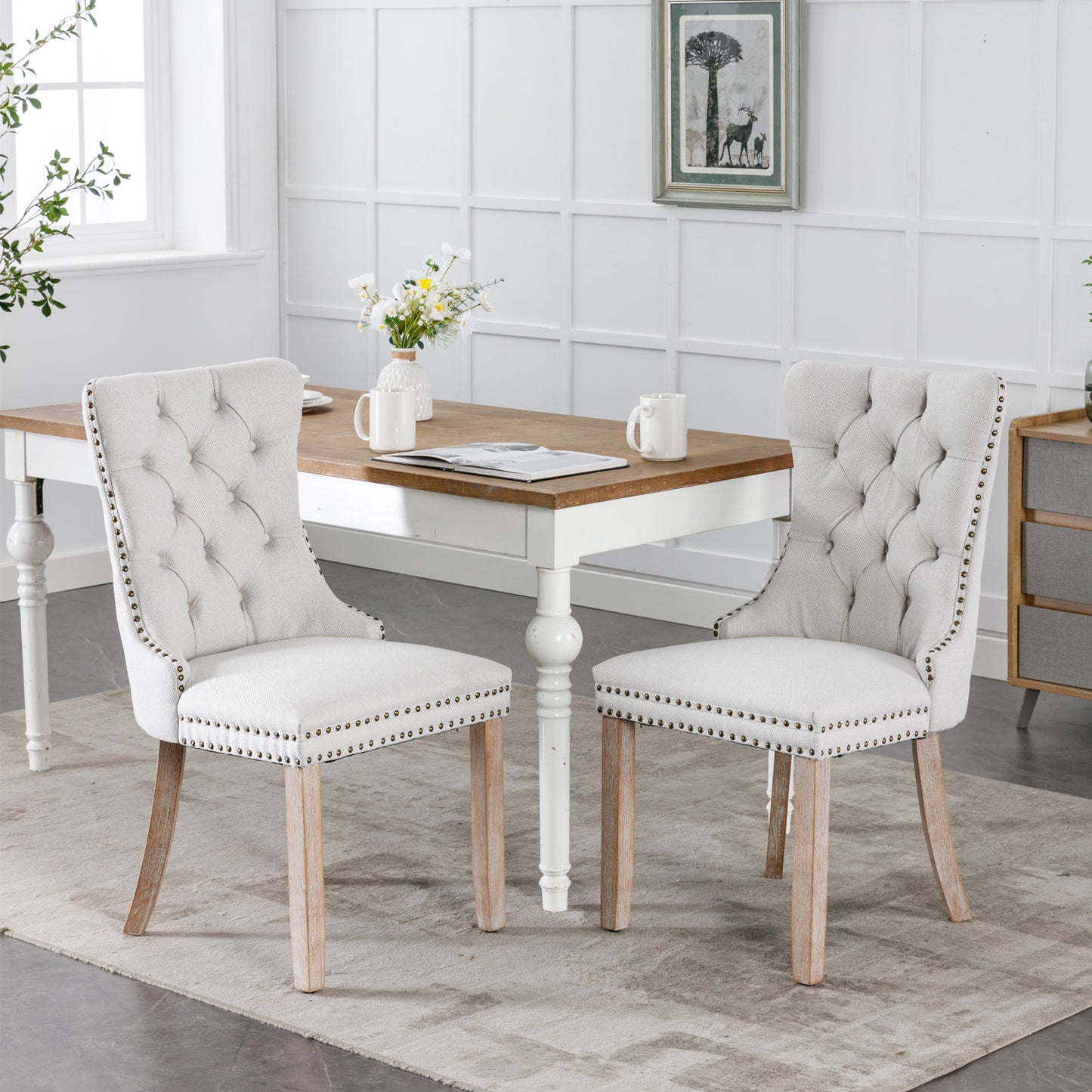 Two tufted cream upholstered dining chairs with nailhead trim and natural wood legs