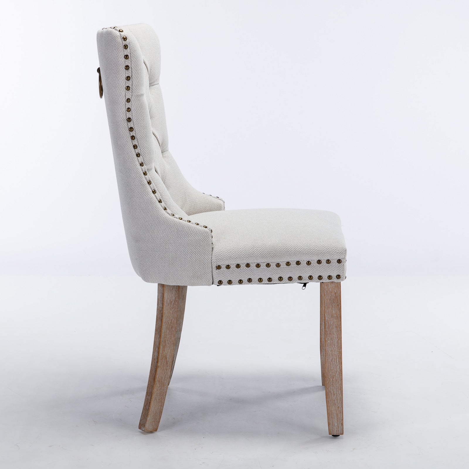 Tufted linen dining chair in cream with antique brass nailhead trim and wooden legs