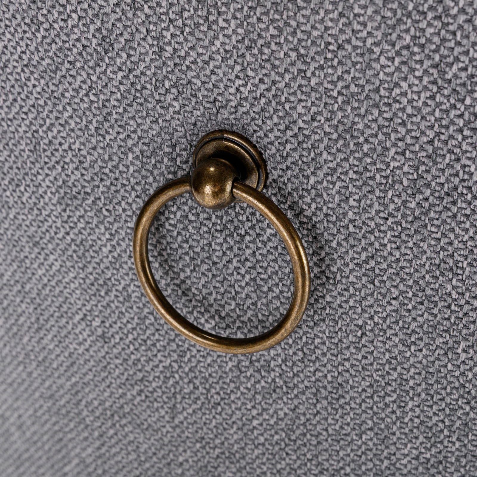 Antique brass ring pull on textured gray fabric drawer