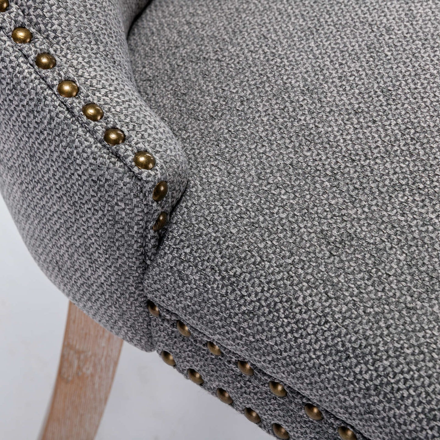 Gray upholstered armchair with brass nailhead trim and wooden legs