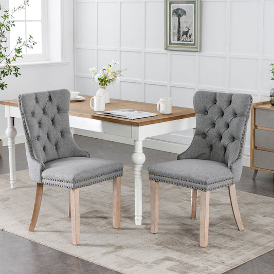 Tufted grey fabric dining chair with studded trim and light wood legs