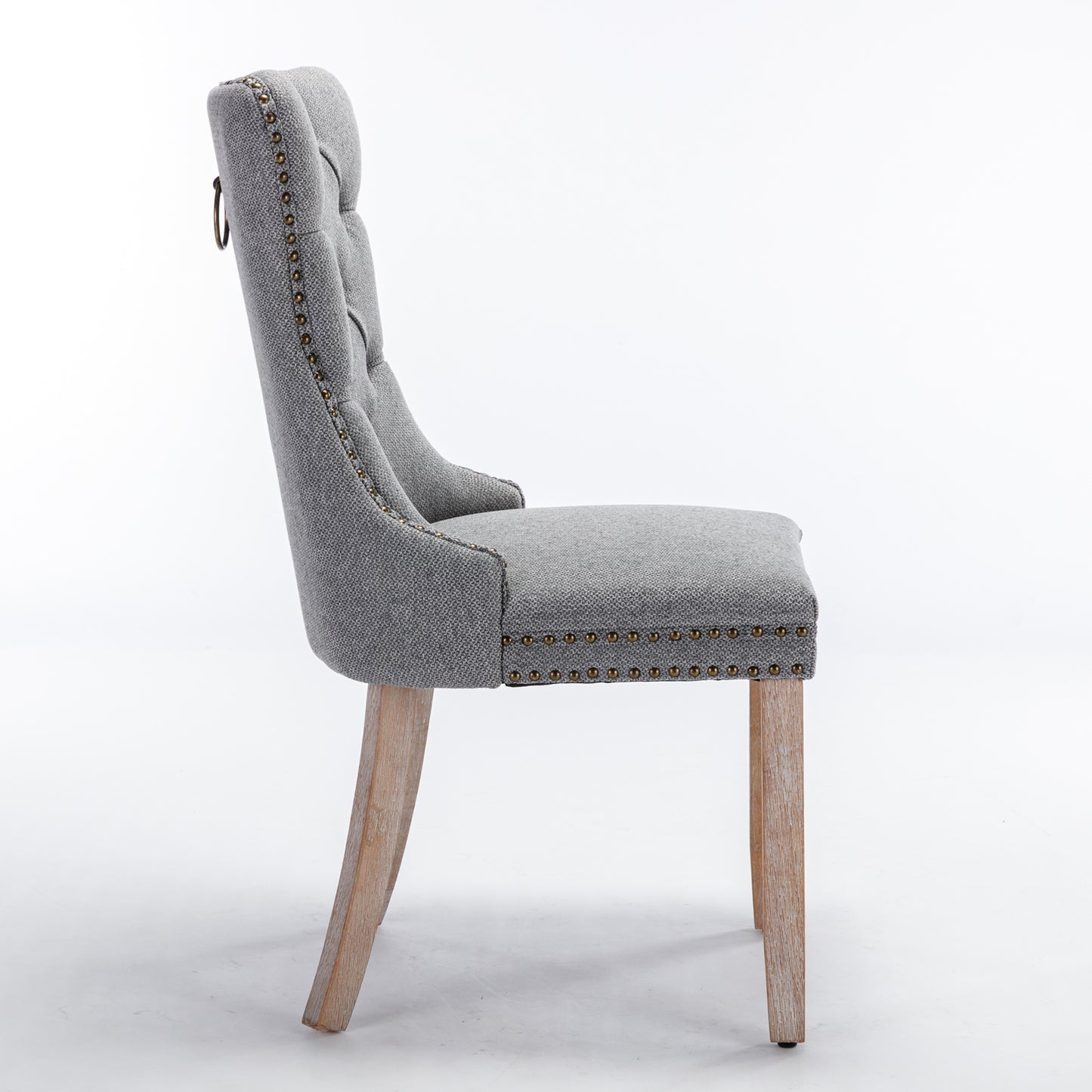 Grey upholstered dining chair with tufted back and brass nailhead trim