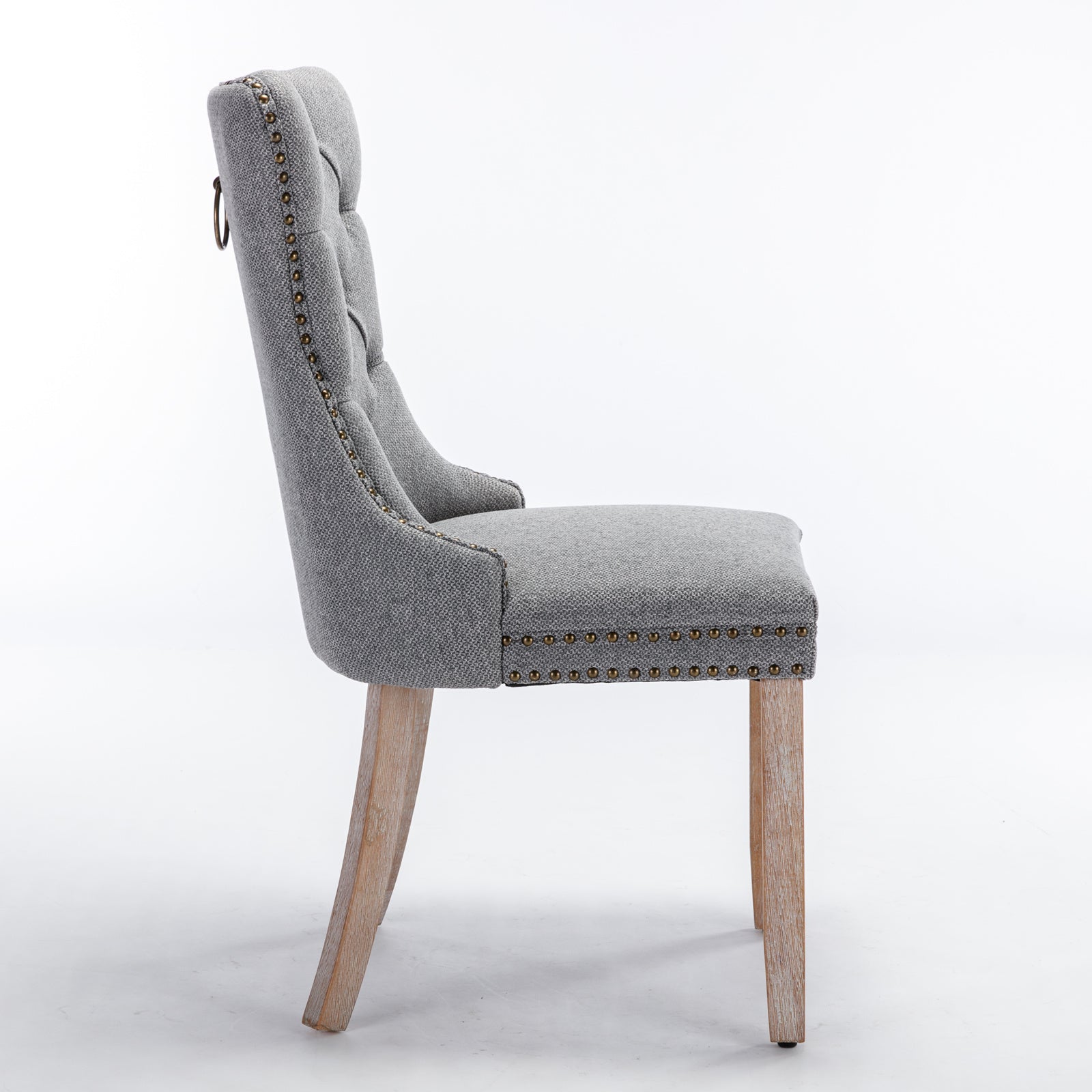 Grey upholstered dining chair with tufted back and brass nailhead trim