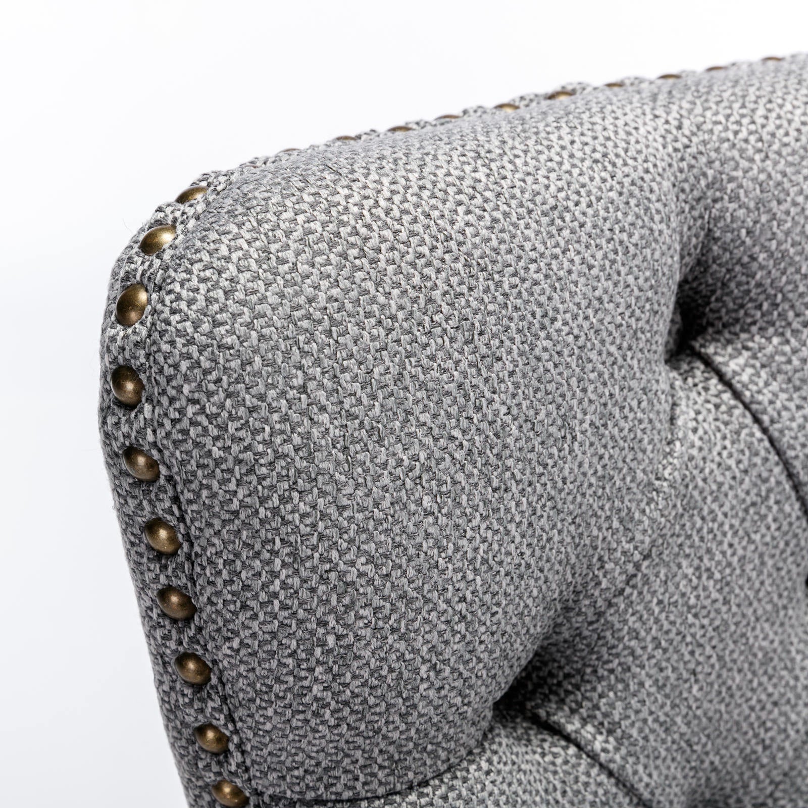 Tufted gray fabric armchair with brass nailhead trim detail