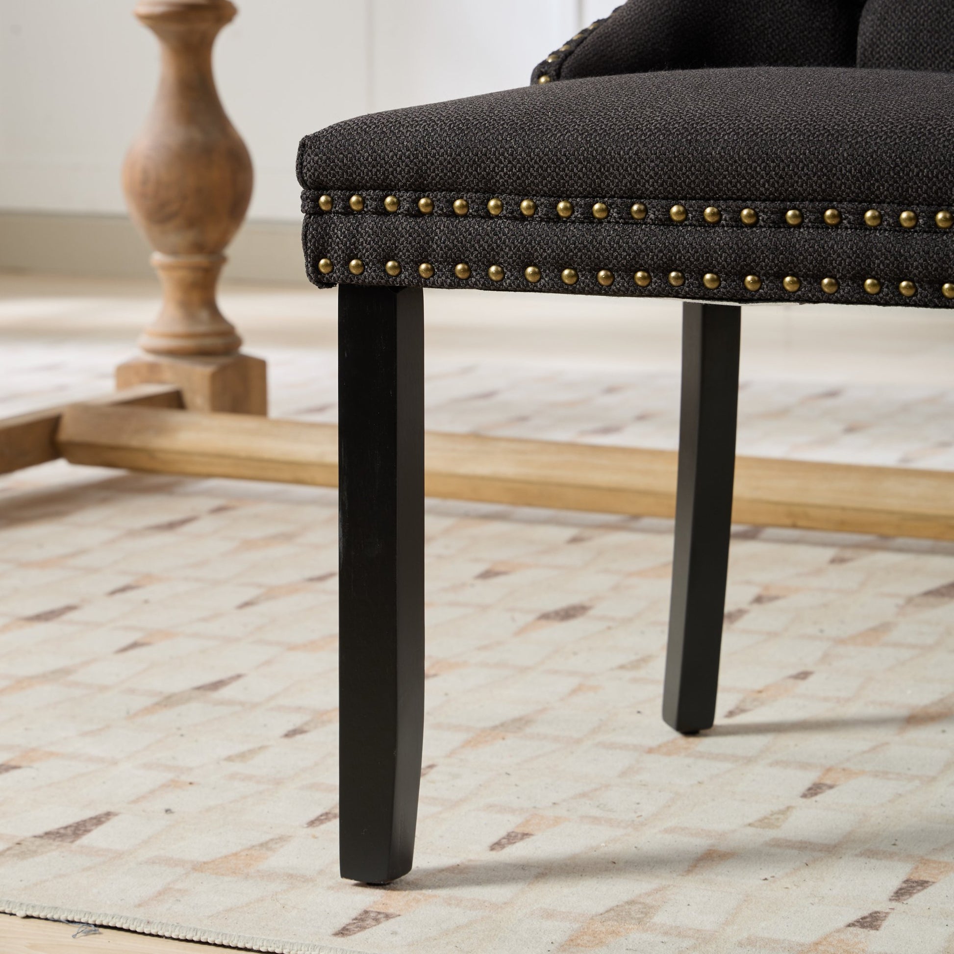 Dark grey upholstered armchair with brass nailhead trim and black legs