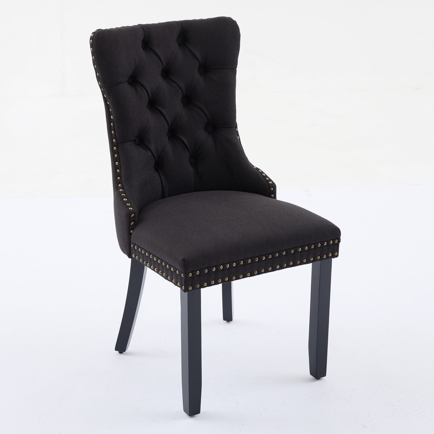 Black tufted dining chair with antique brass nailhead trim