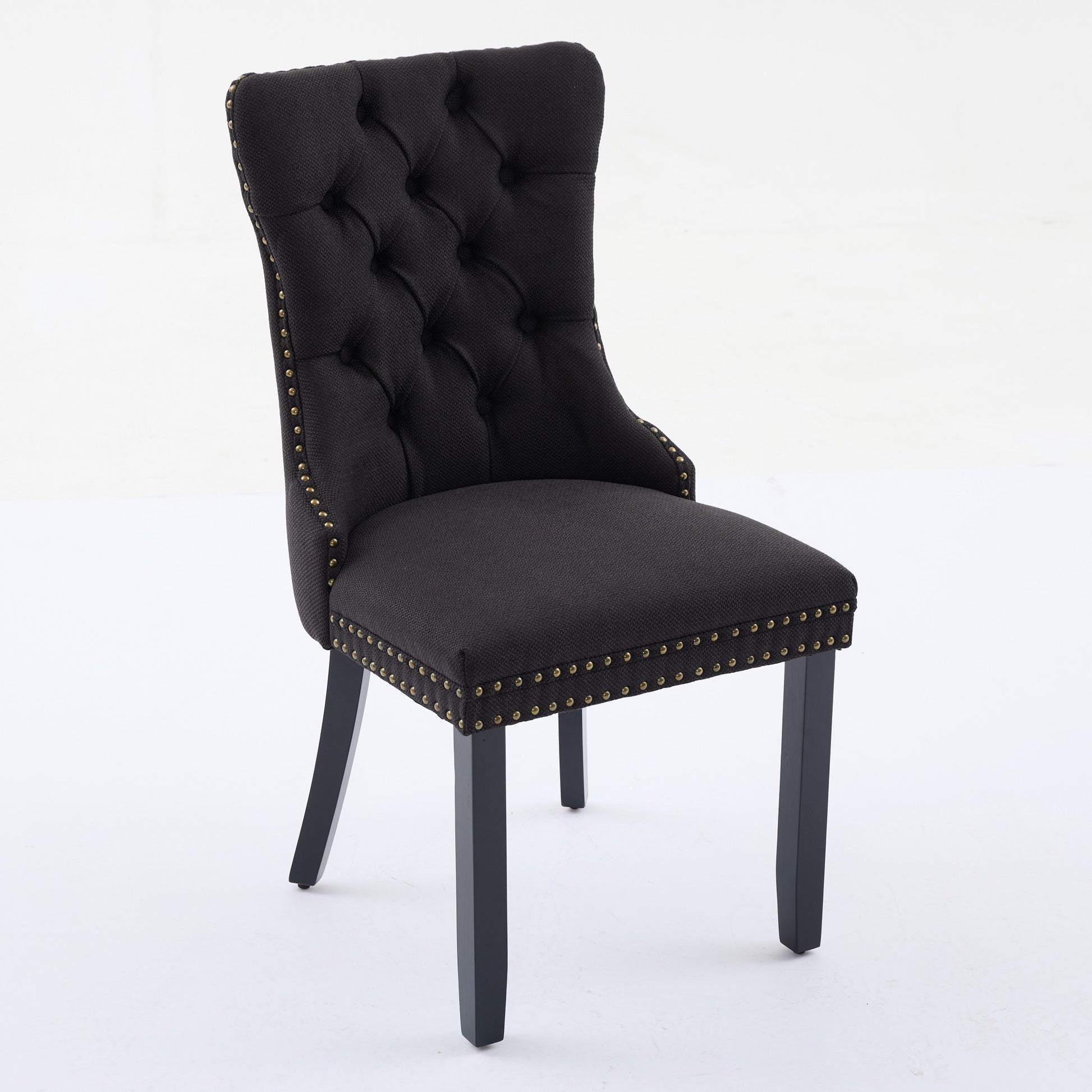 Black tufted dining chair with antique brass nailhead trim