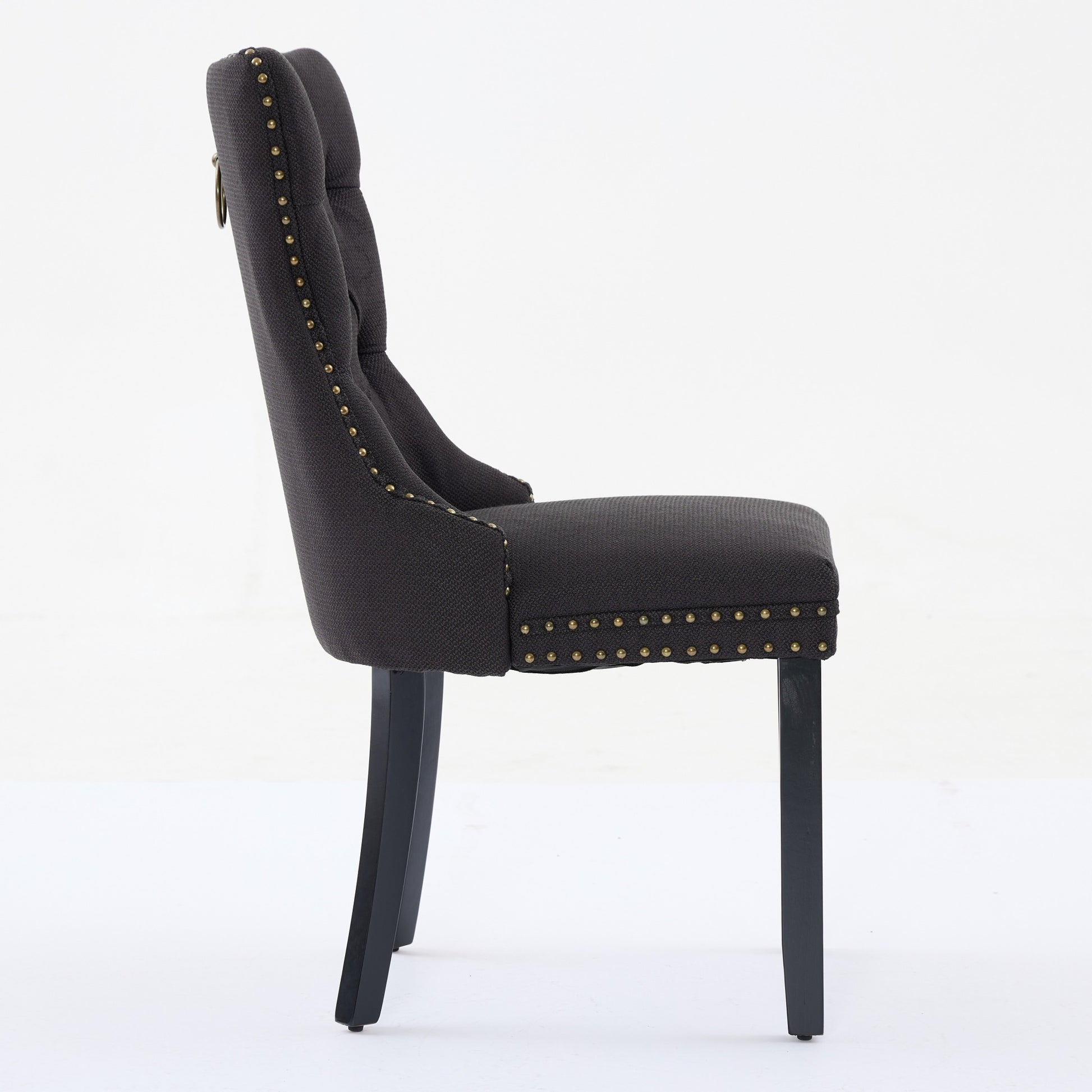 Dark grey tufted accent chair with brass nailhead trim and ring pull