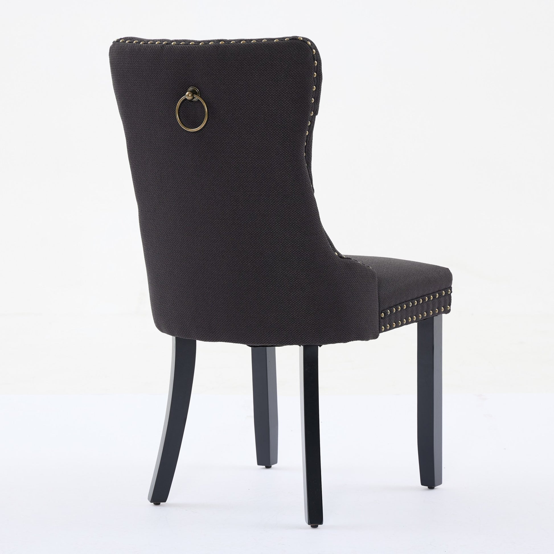 Dark gray upholstered dining chair with brass nailhead trim and ring pull