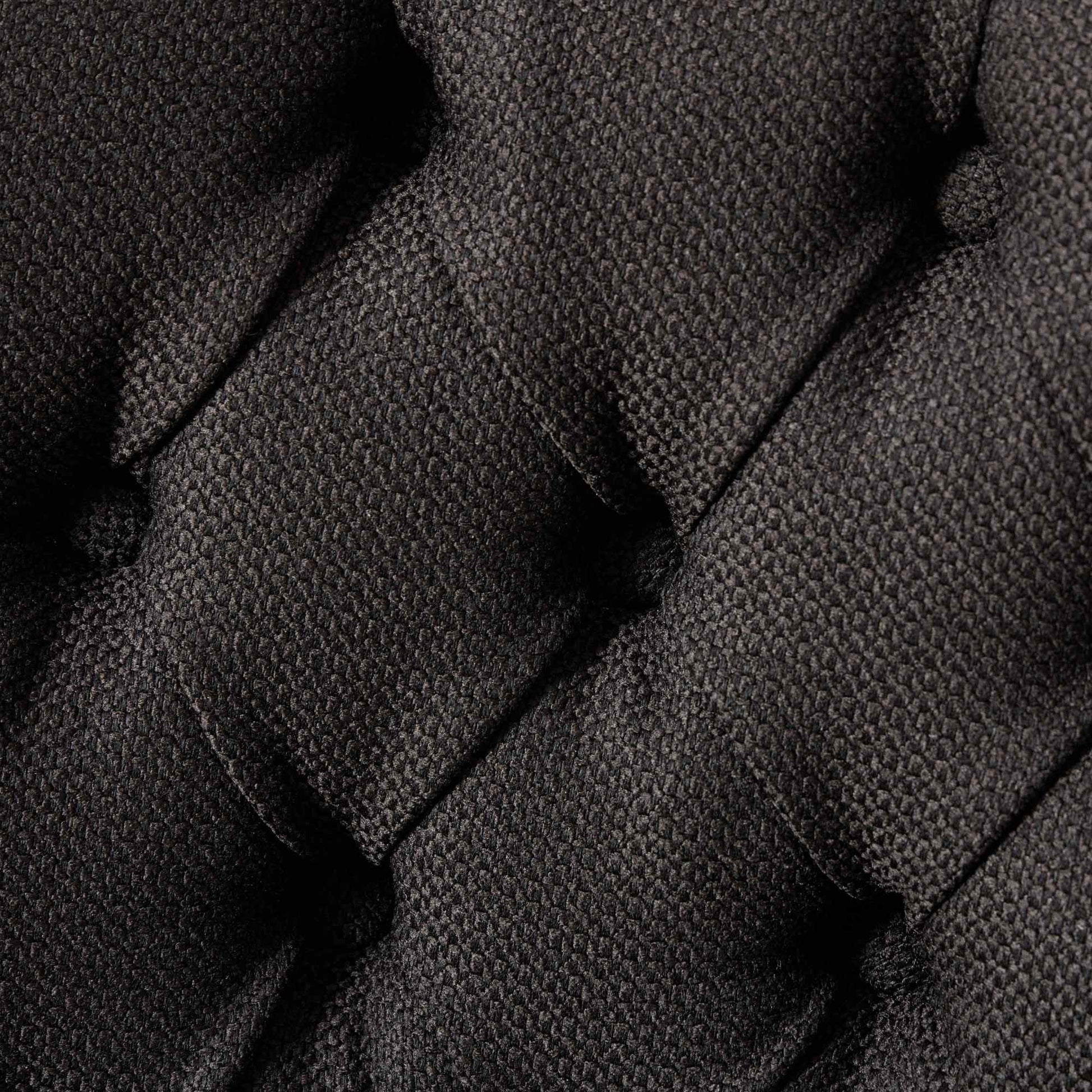 Closeup of dark grey woven fabric texture on a tufted accent chair