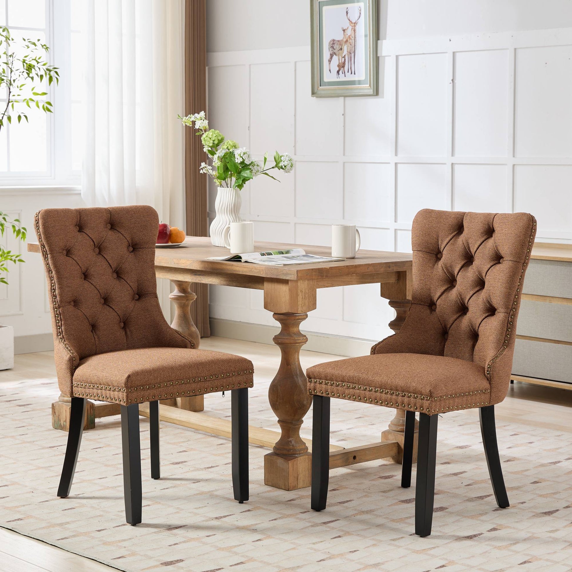 Tufted brown fabric dining chair with antique brass nailhead trim and dark wood legs