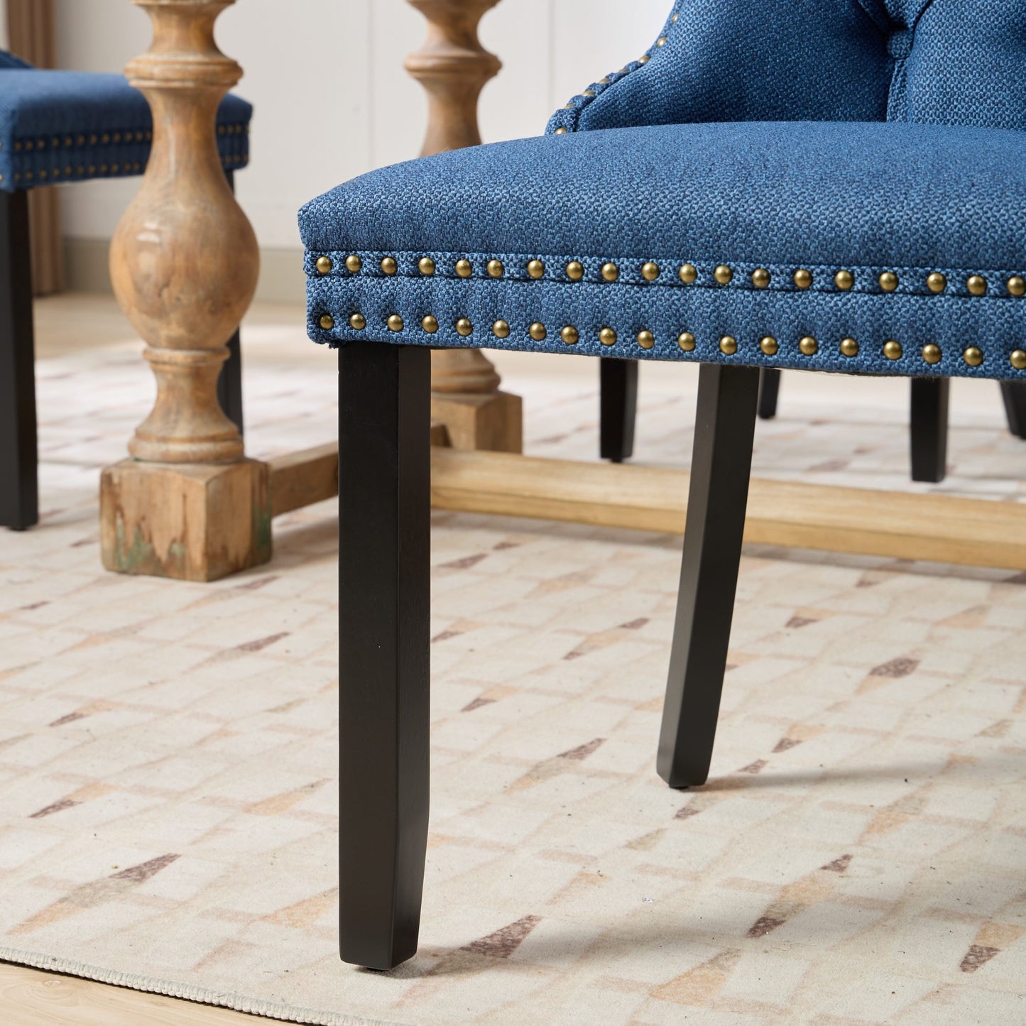 Blue upholstered dining chair with brass nailhead trim and dark wood legs