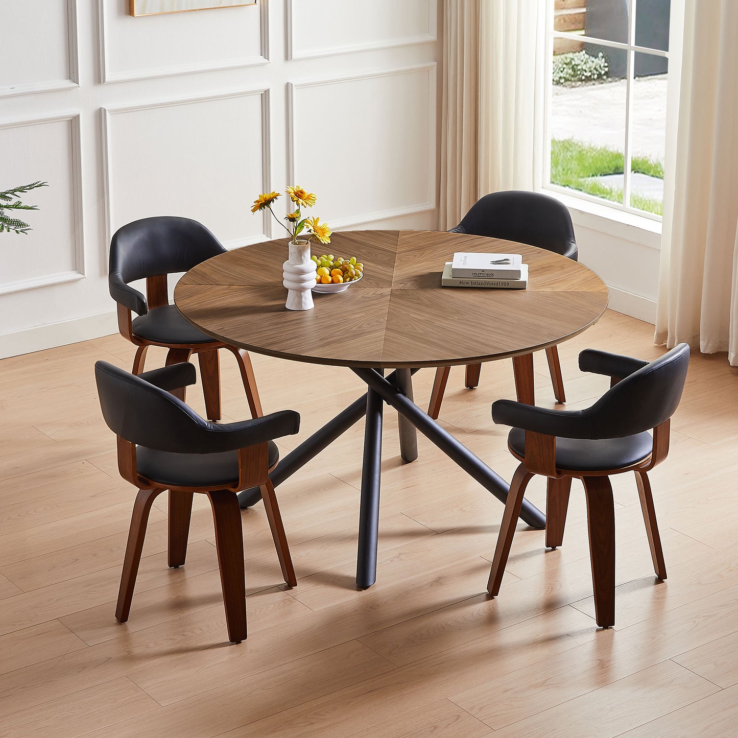 Round walnut dining table with four black leather chairs