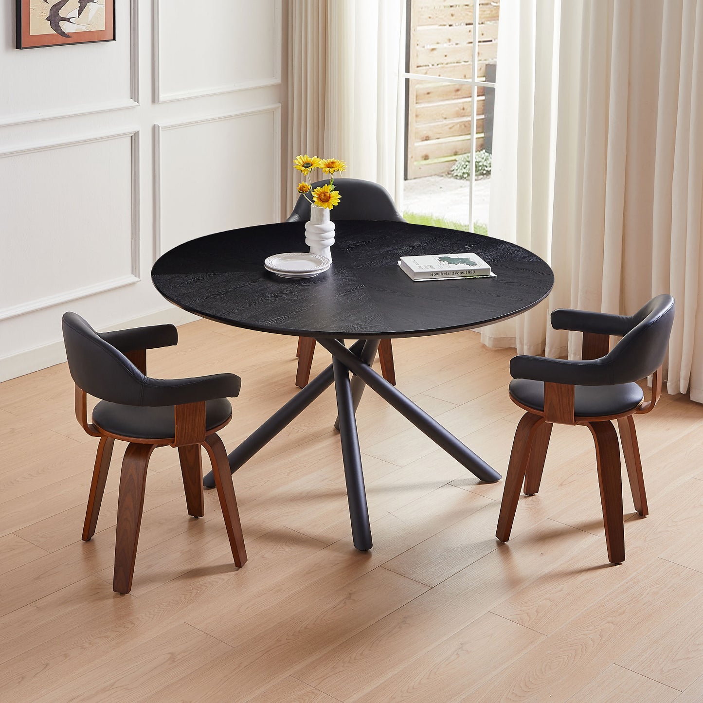Black round dining table with wooden chairs and floral vase