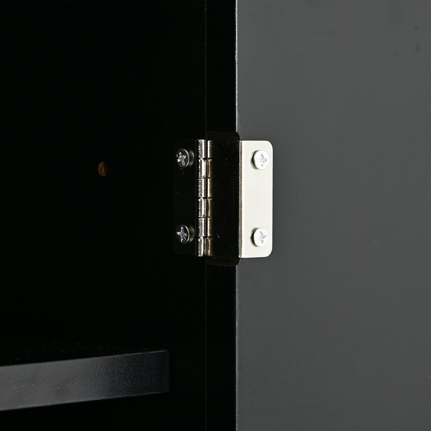 Closeup of silver cabinet hinge on black door frame