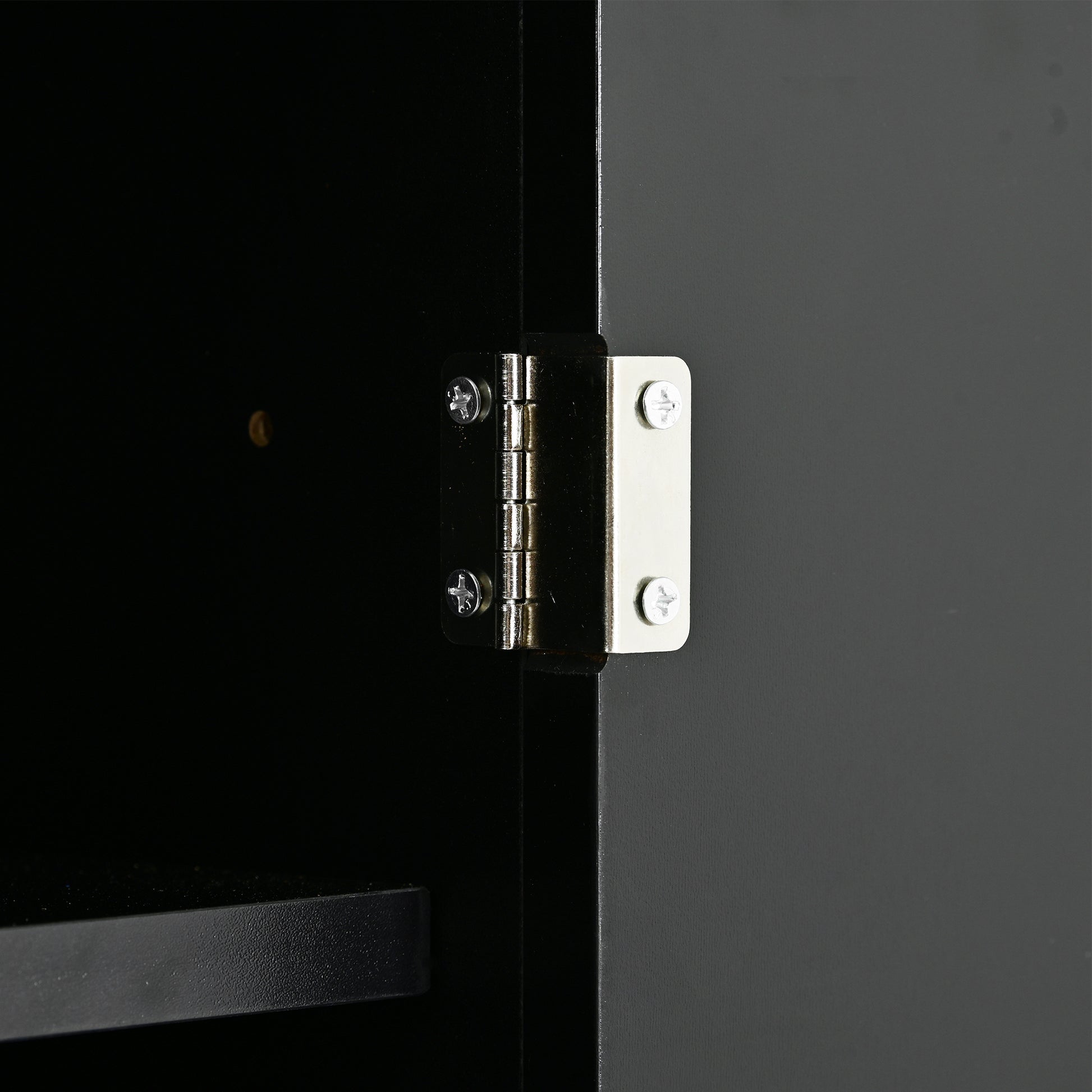 Closeup of silver cabinet hinge on black door frame