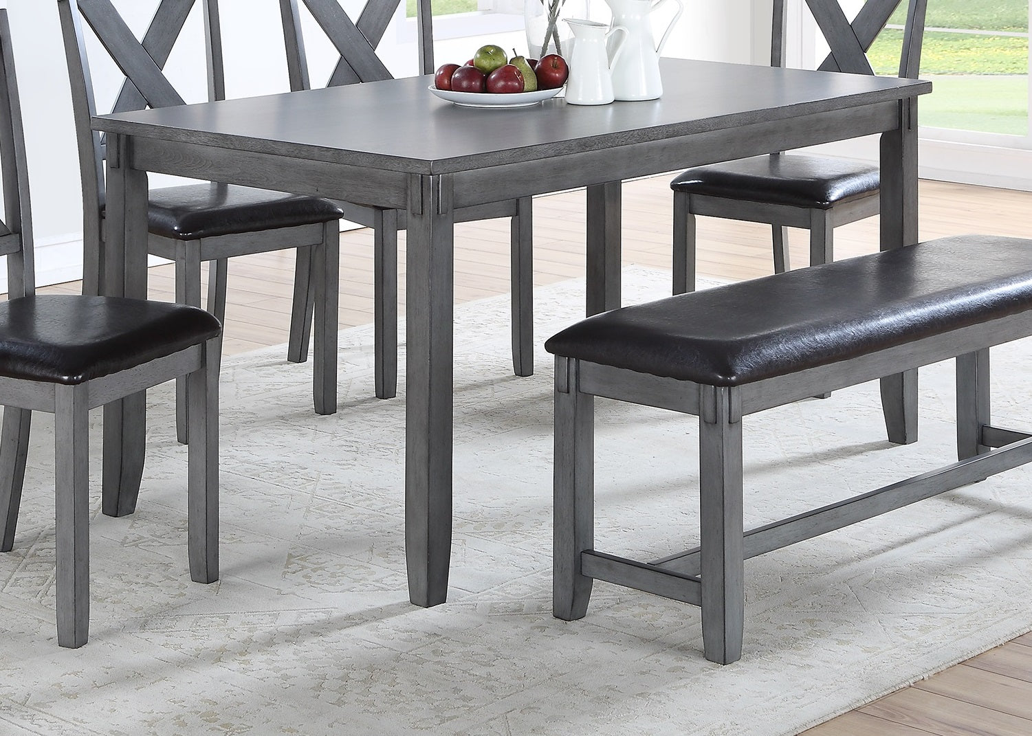Gray wood dining table with dark upholstered chairs and bench