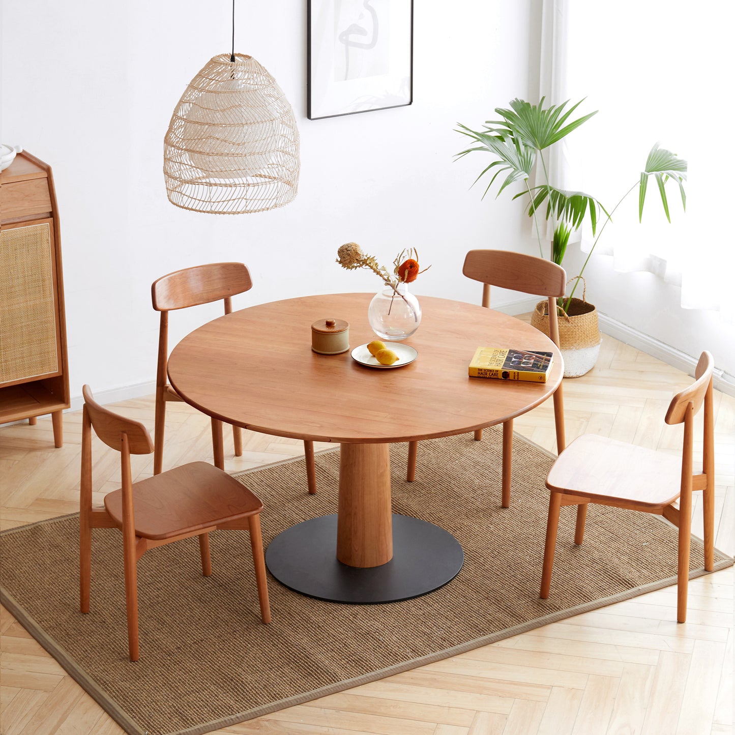 Round wooden dining table with four chairs and woven pendant light