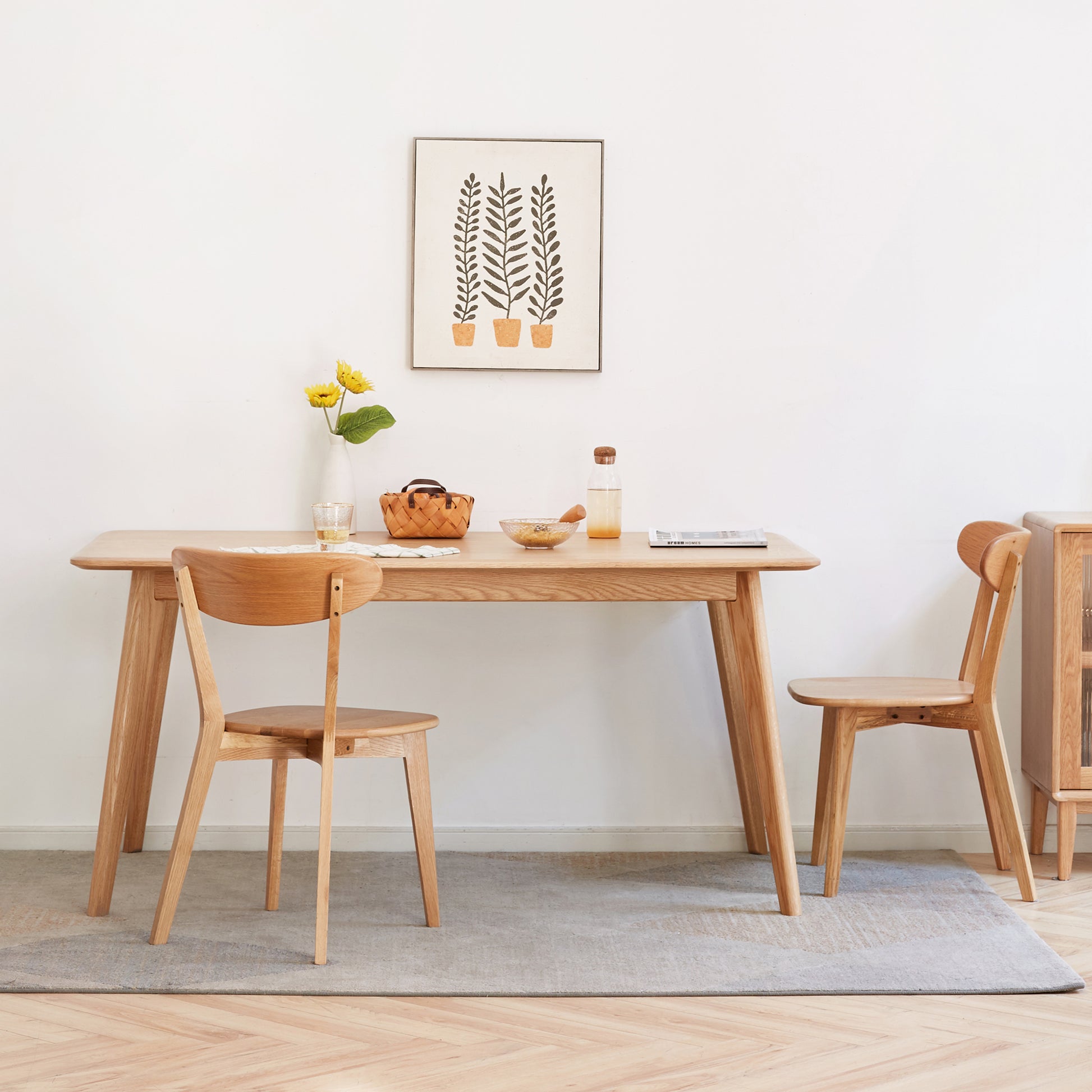 Solid wood dining table with curved edges and two oak chairs