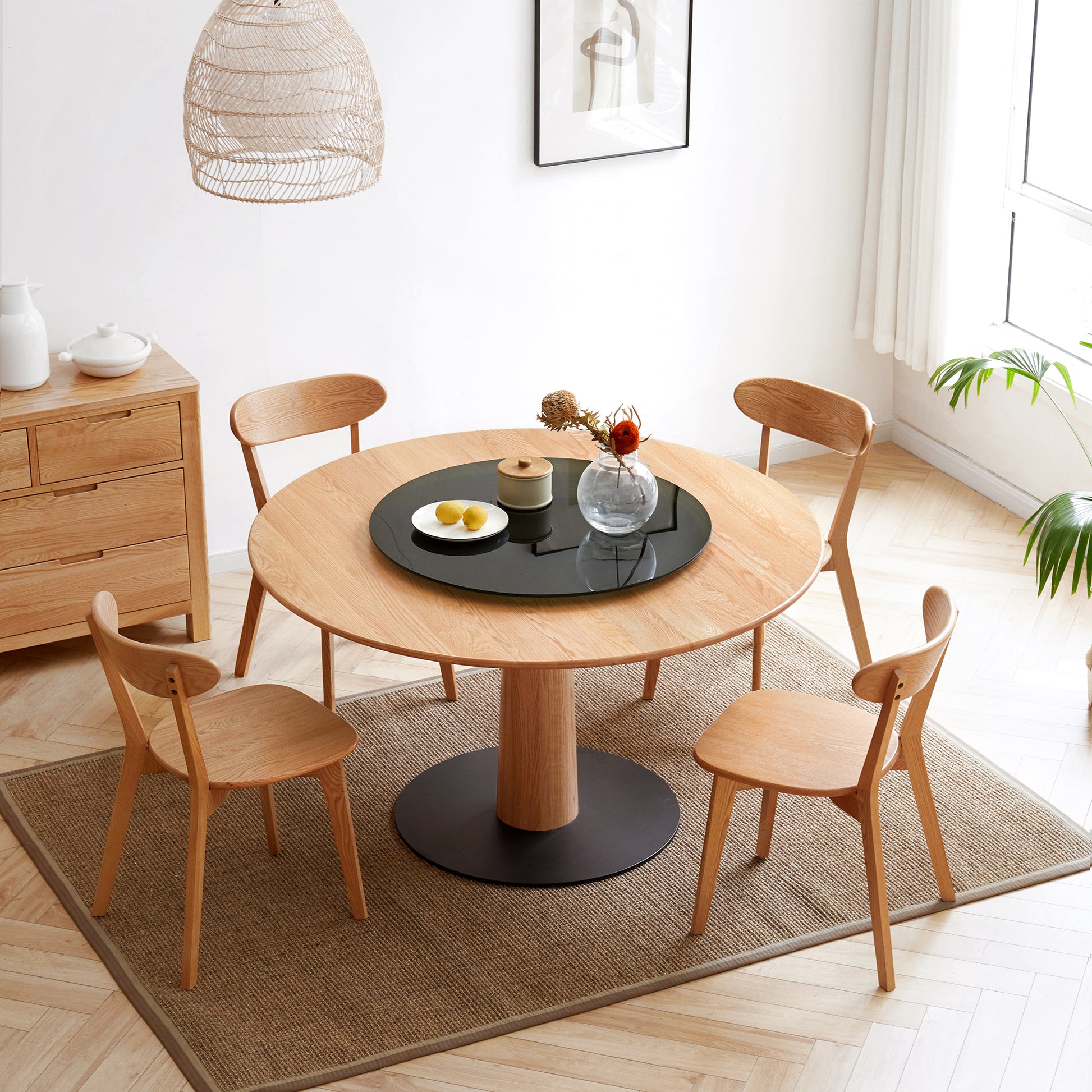 Solid oak pedestal dining table with four wooden chairs and decorative centerpiece