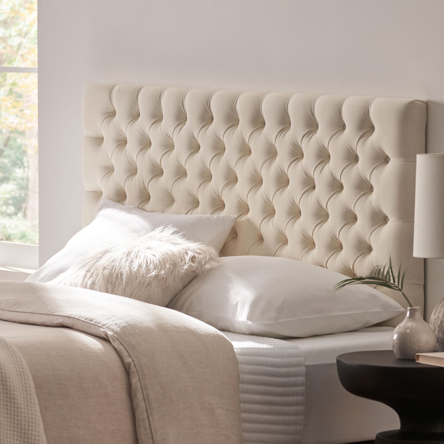 Cream upholstered diamond tufted headboard with plush pillows