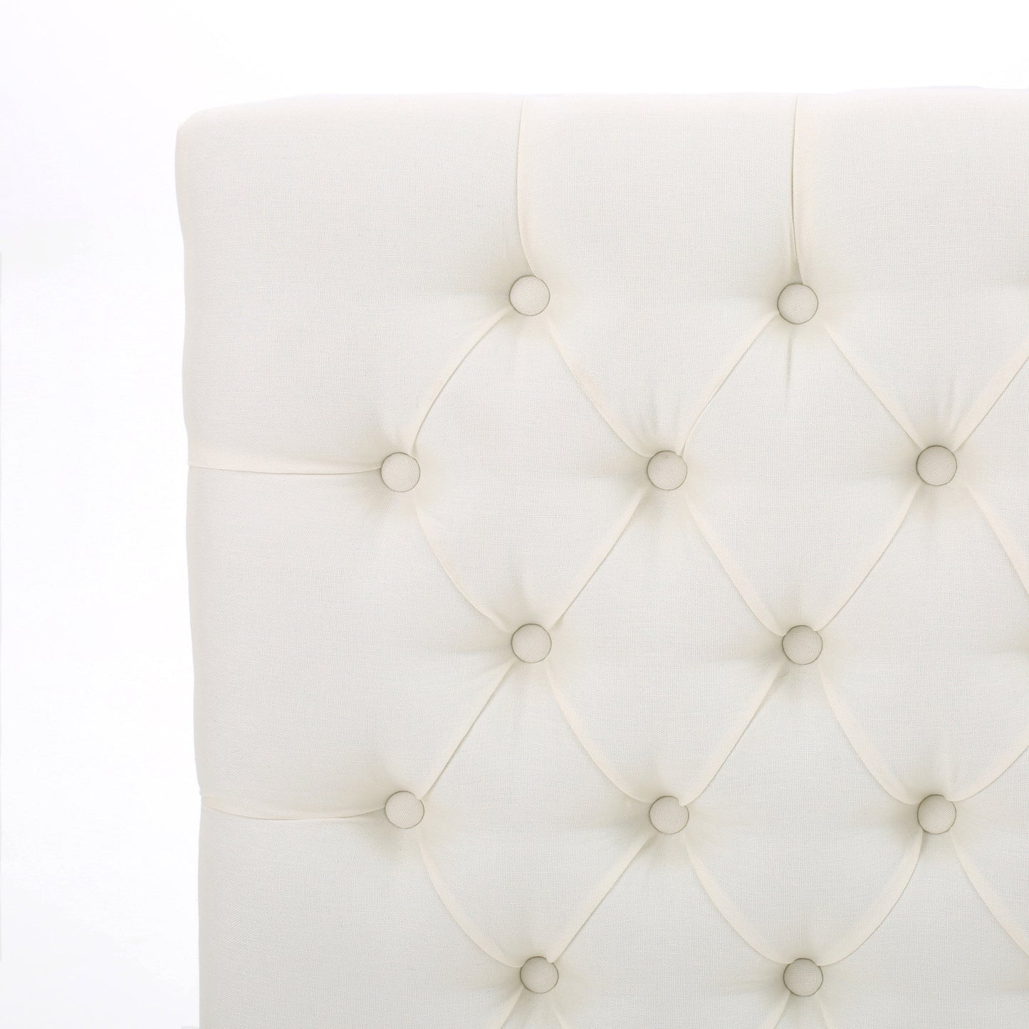 Closeup of diamondtufted ivory fabric headboard with button accents