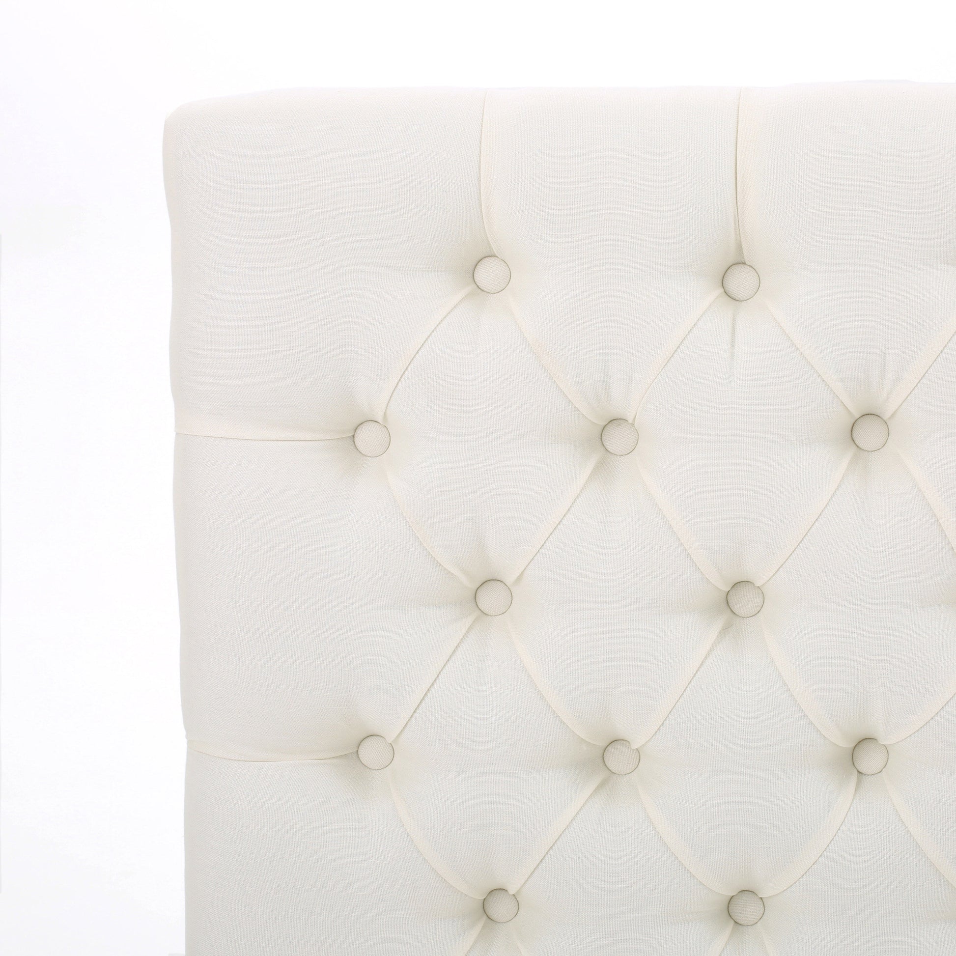 Closeup of diamondtufted ivory fabric headboard with button accents