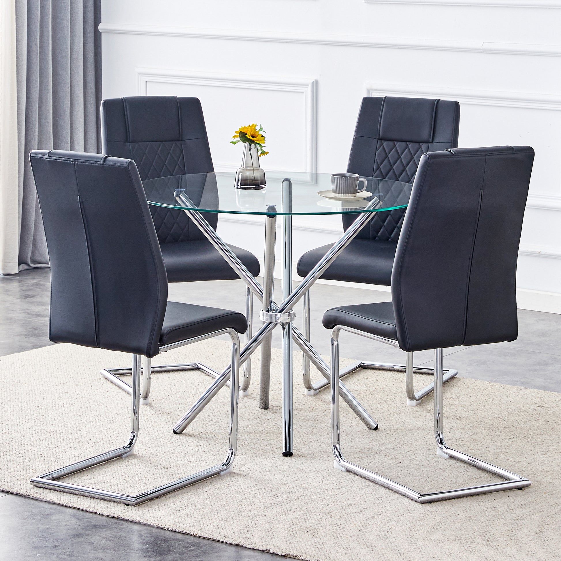 Round glass dining table with four black leatherette chairs
