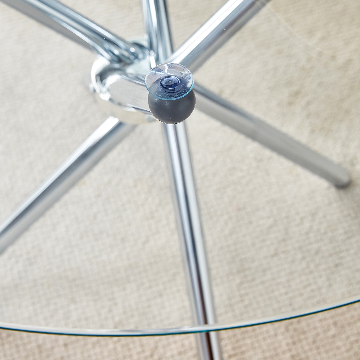 Close up of a round glass tabletop edge and chrome pedestal base with suction cups