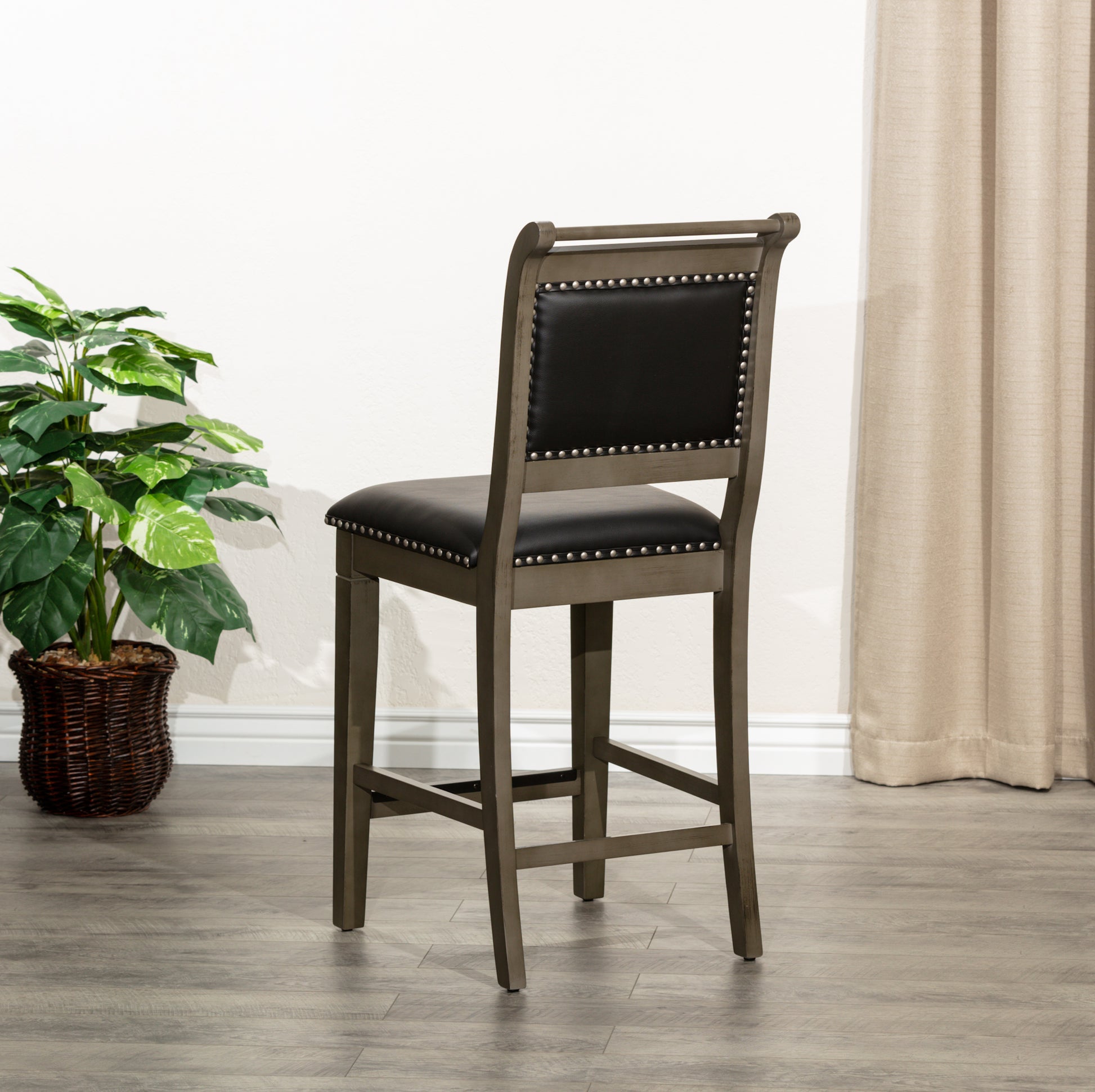 Gray wooden counter stool with black faux leather seat and silver nailhead trim