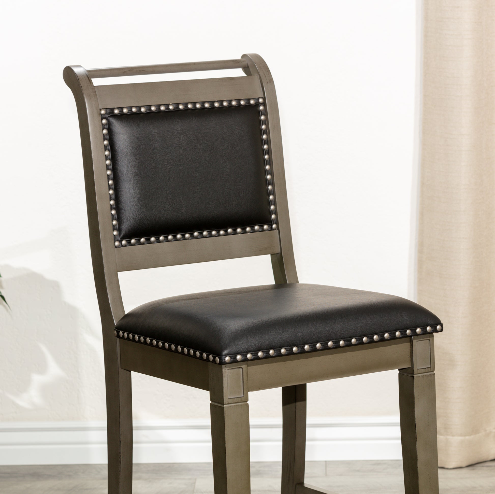 Gray wooden bar stool with black leather seat and silver nailhead trim