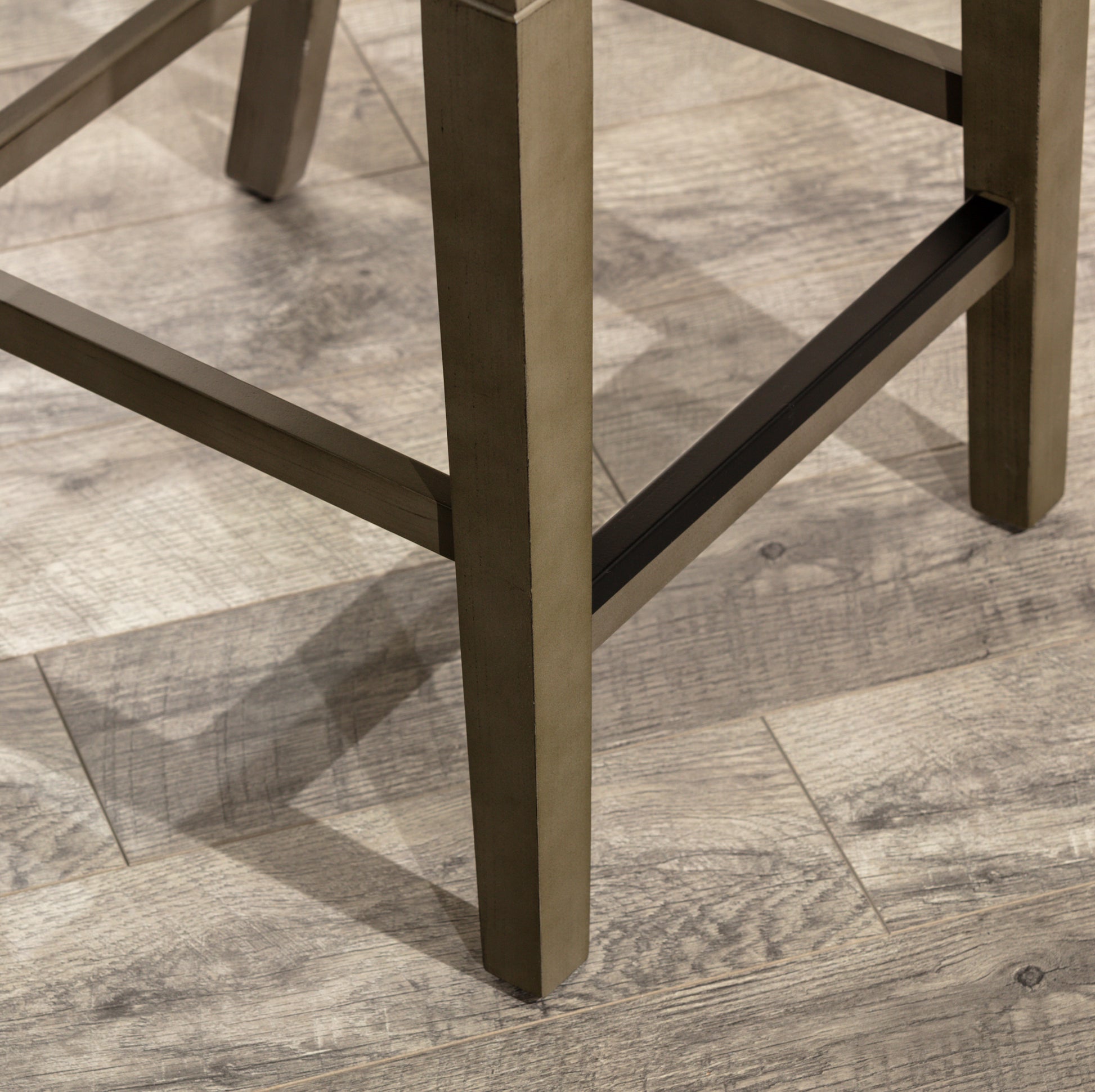 Close up of dark wood bar stool legs on a distressed wood floor