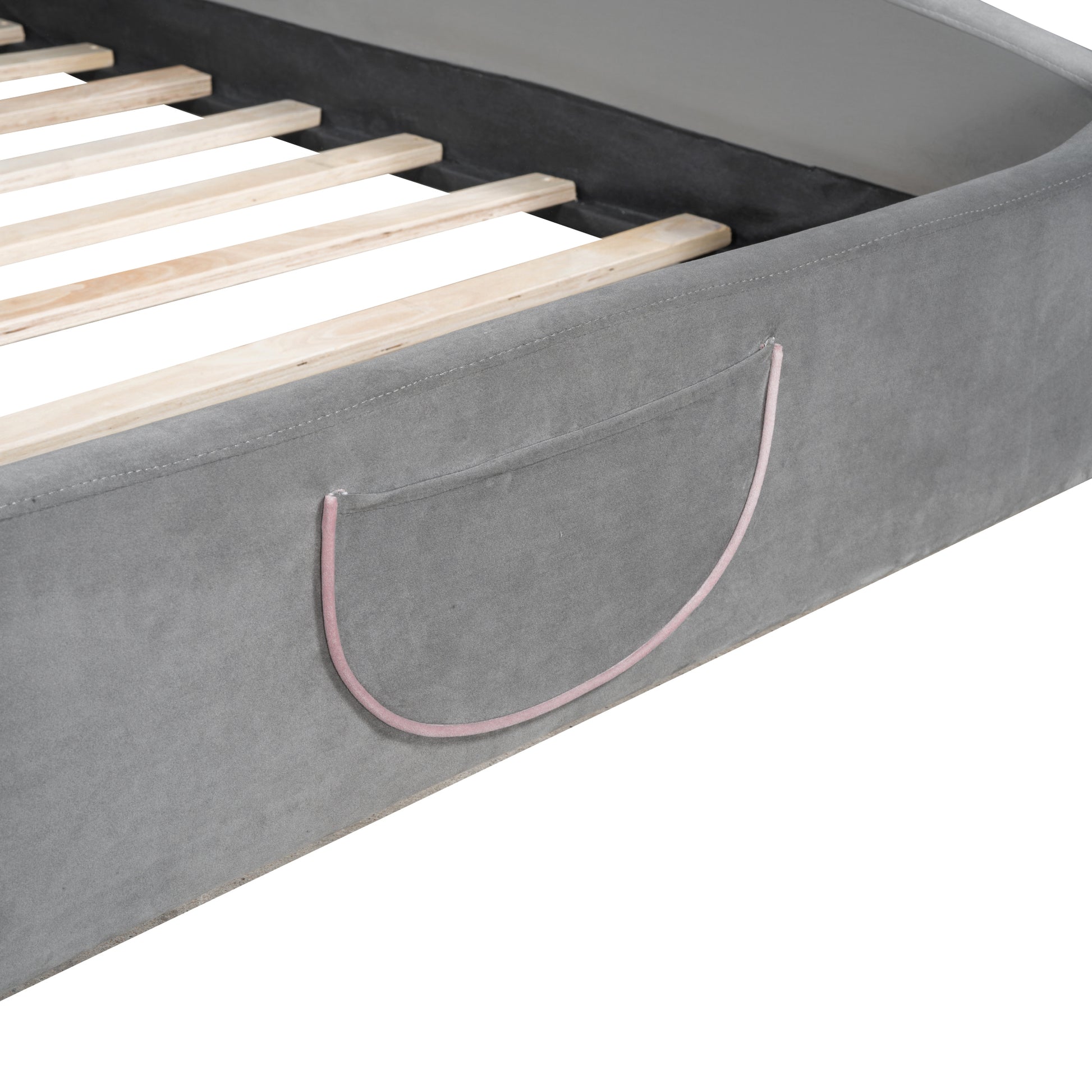 Closeup of a gray upholstered bed frame with wooden slats and a pink accent pocket