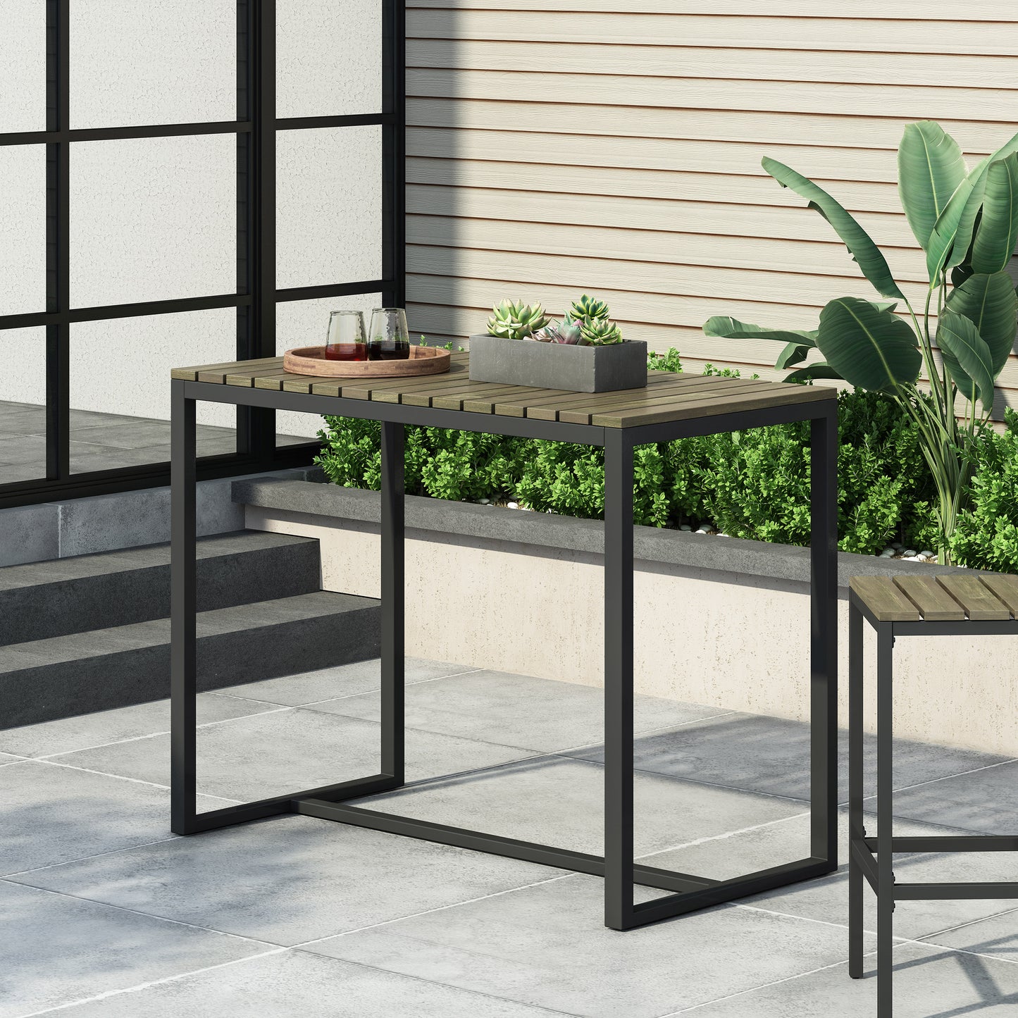 Modern outdoor bar table with woodslat top and black metal frame on patio