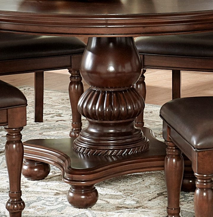 Ornate pedestal of a dark mahogany dining table with carved details